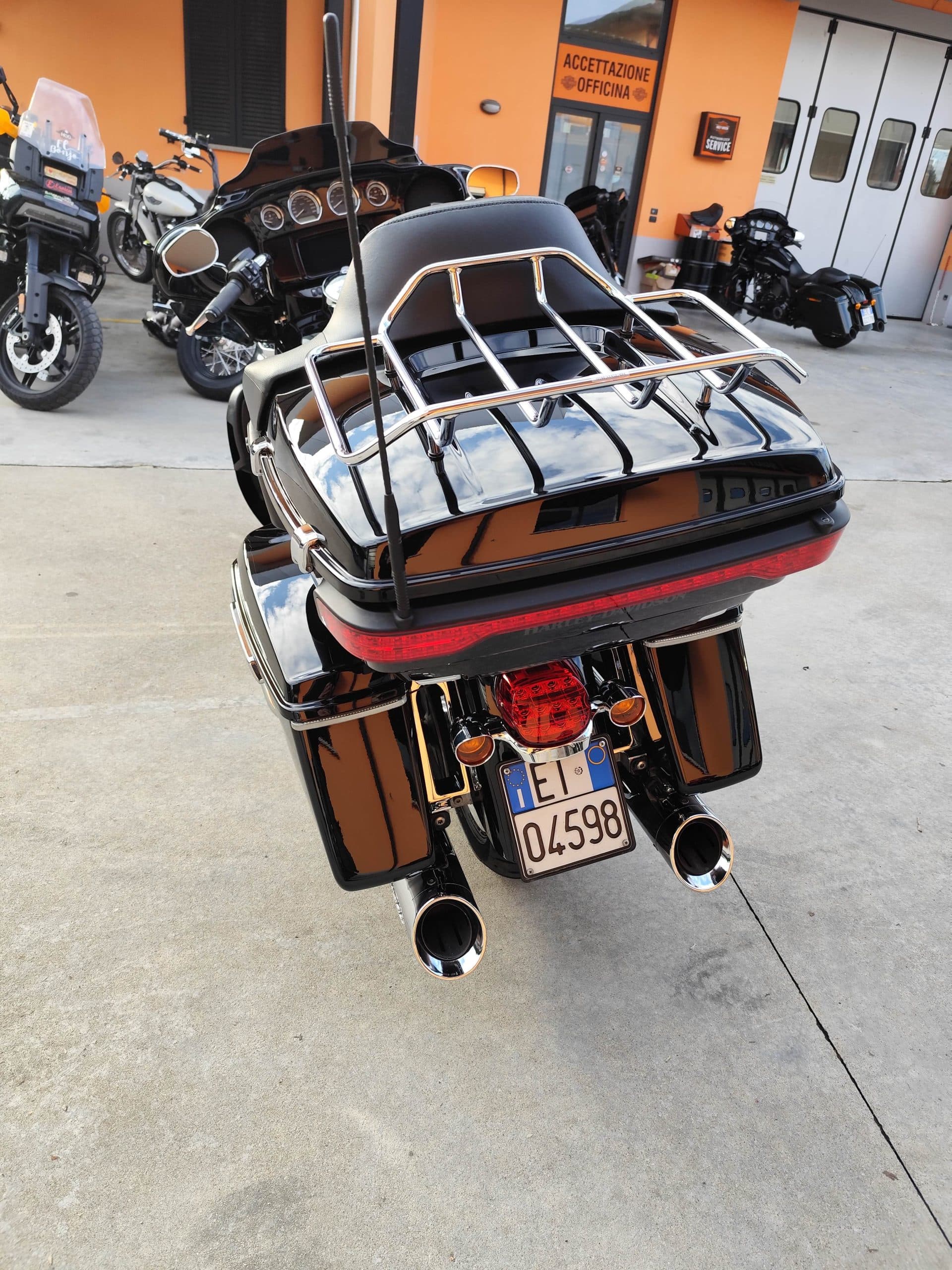 Harley-Davidson touring nera, vista posteriore, con portapacchi, borse laterali e targa italiana ET 04598, in concessionaria.
