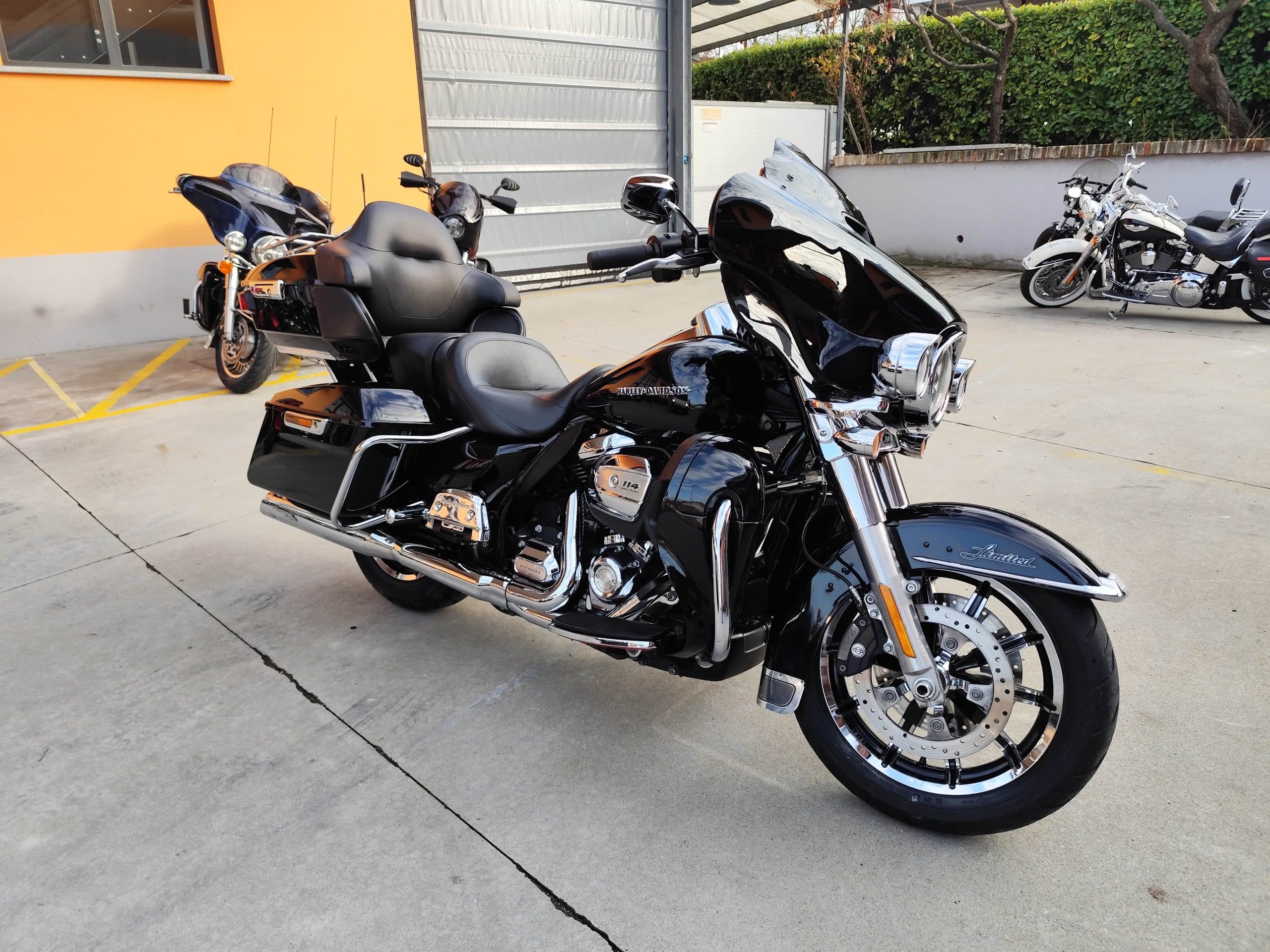 Harley-Davidson Ultra Limited 114 nera lucida, in esposizione presso la concessionaria. Dettagli cromati e altre moto in background.