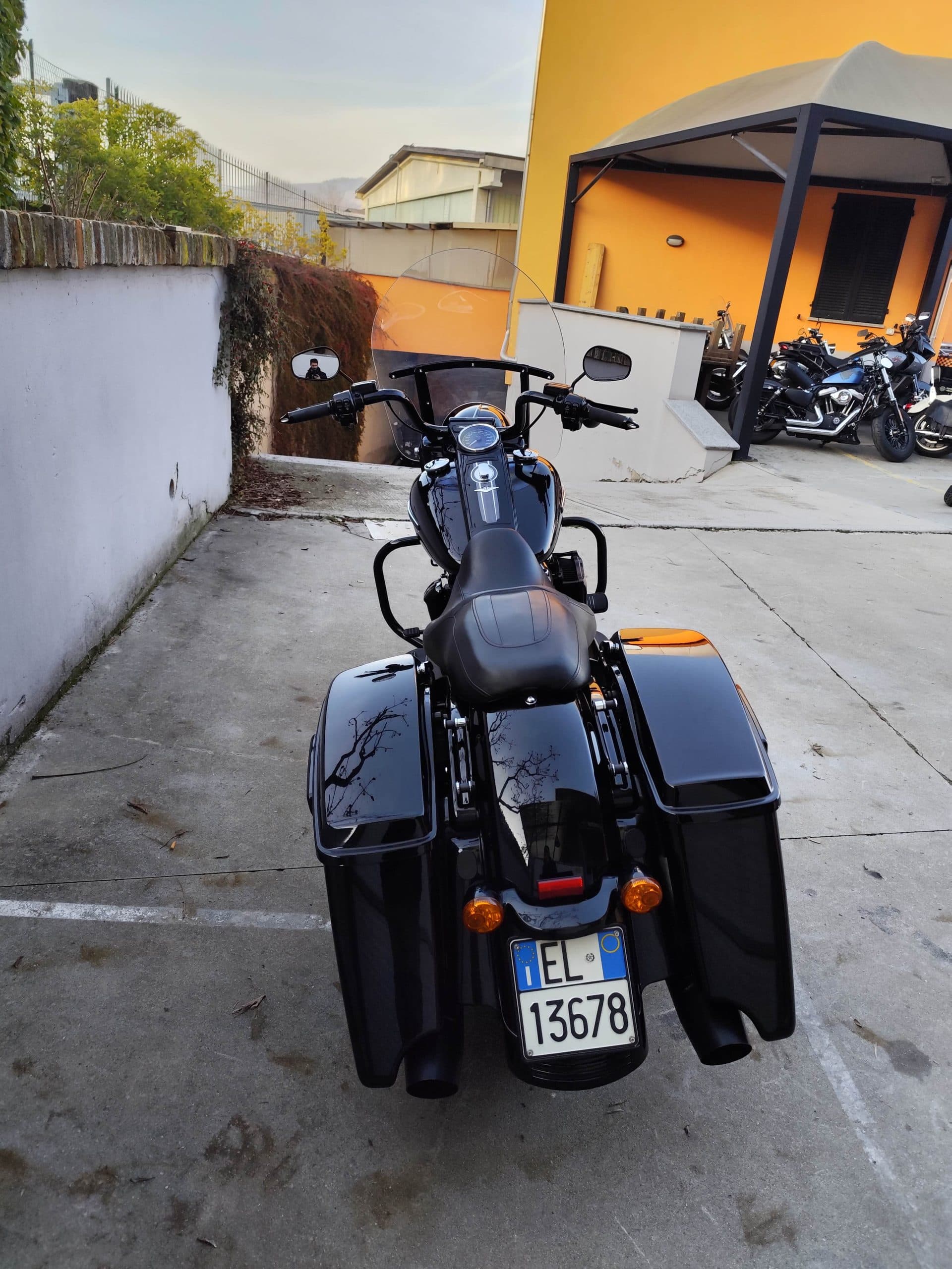 Harley-Davidson nera, modello touring con borse laterali rigide e doppio scarico, parcheggiata in area esterna. Targa italiana visibile.