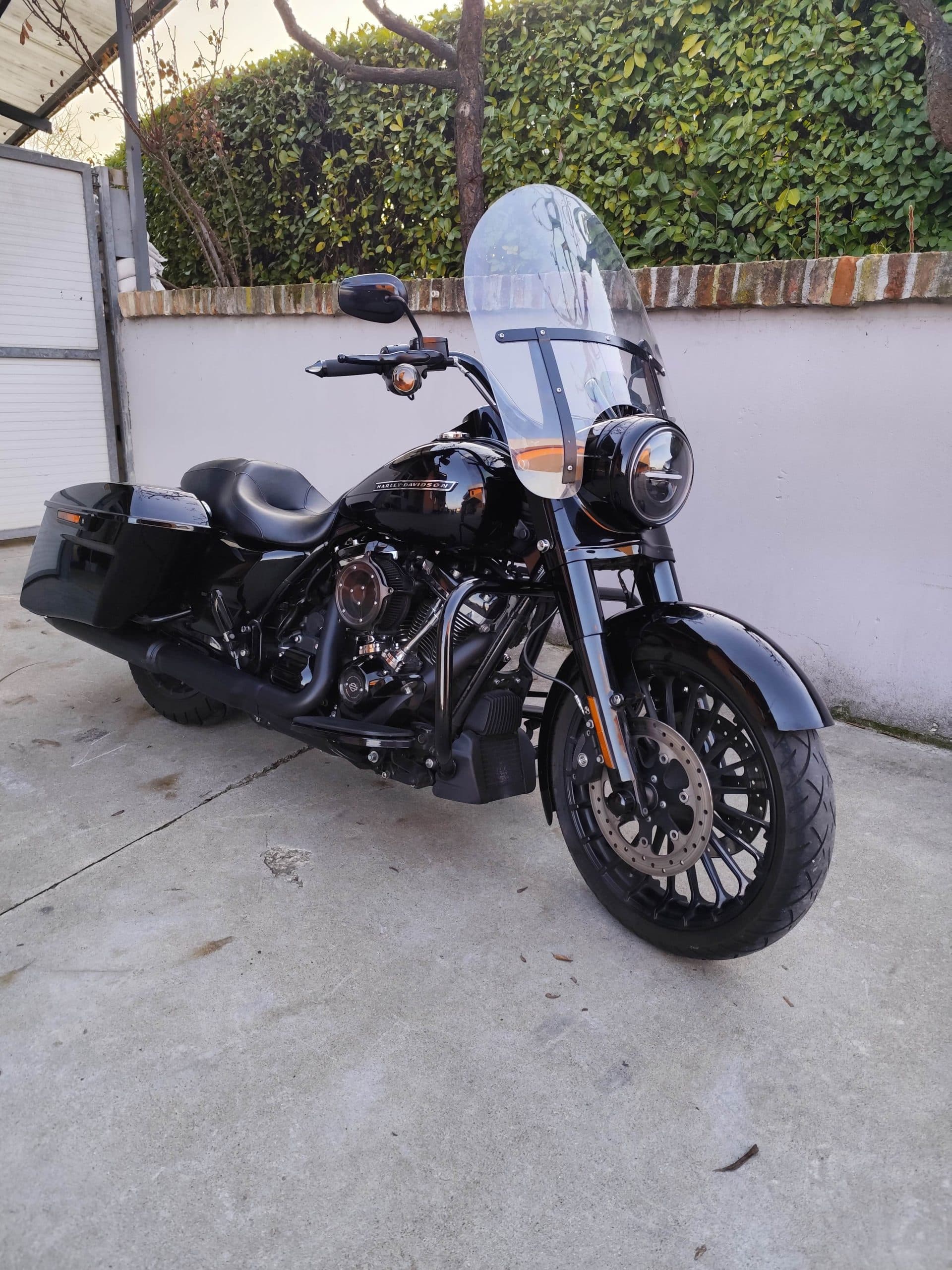 Harley-Davidson nera, modello touring, parcheggiata su cemento. Dettagli motore, parabrezza e borse laterali rigide. Perfetta per test ride.