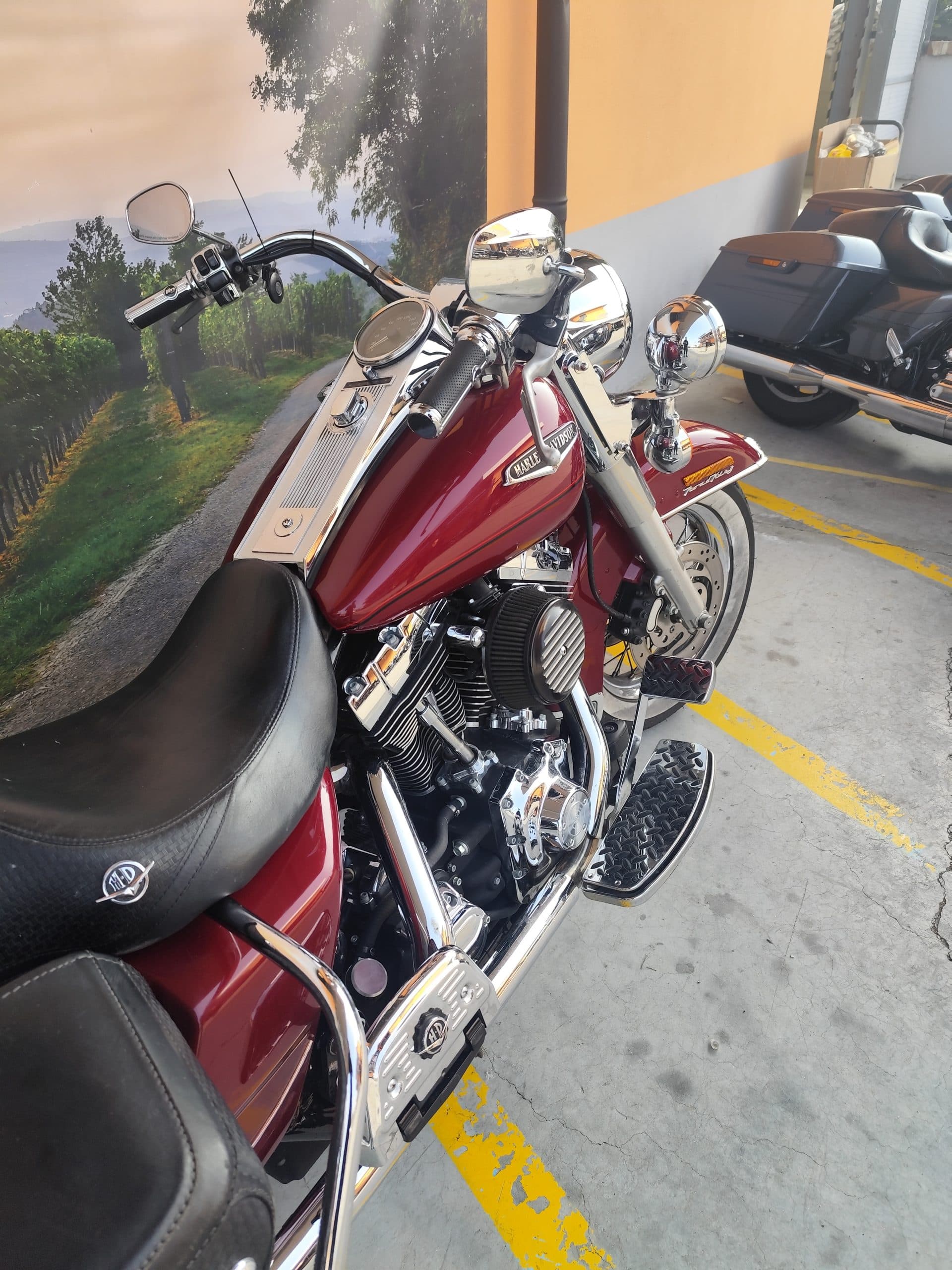 Harley-Davidson rossa, modello classico, con motore V-twin, cromature lucide, pneumatici whitewall e pedane, esposta in concessionaria.