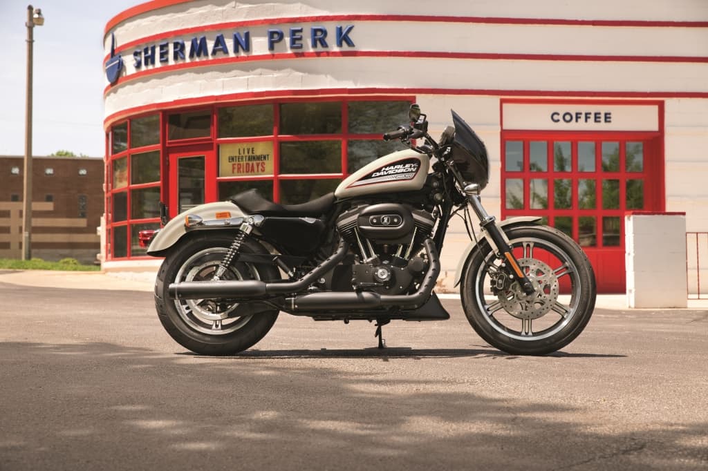 Harley-Davidson Sportster con motore nero e carrozzeria crema, parcheggiata davanti al Sherman Perk. Dettagli ruote e carenatura. Perfetta per un test ride.