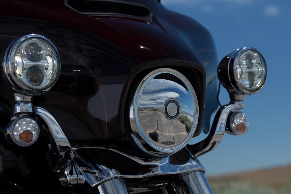 Harley-Davidson, dettaglio del cupolino e fari LED cromati. Il faro principale riflette una strada e il cielo, suggerendo un'esperienza di test ride.