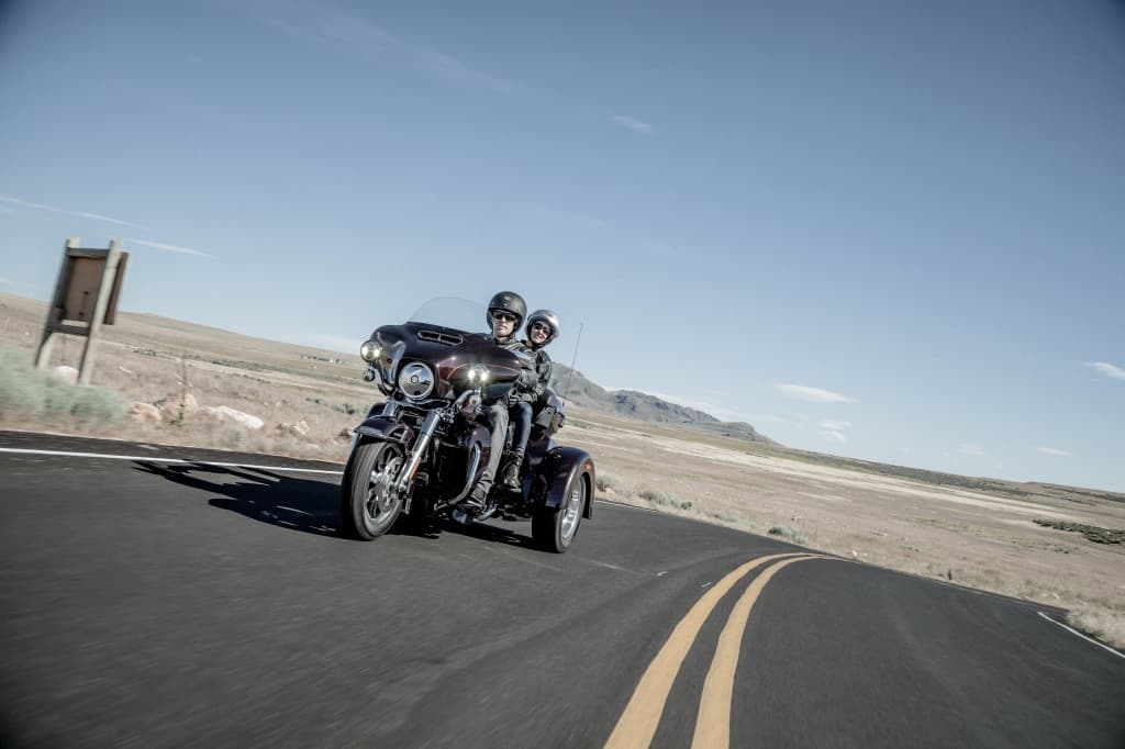 Harley-Davidson Trike con due motociclisti in abbigliamento tecnico su strada aperta. Perfetto per test ride.