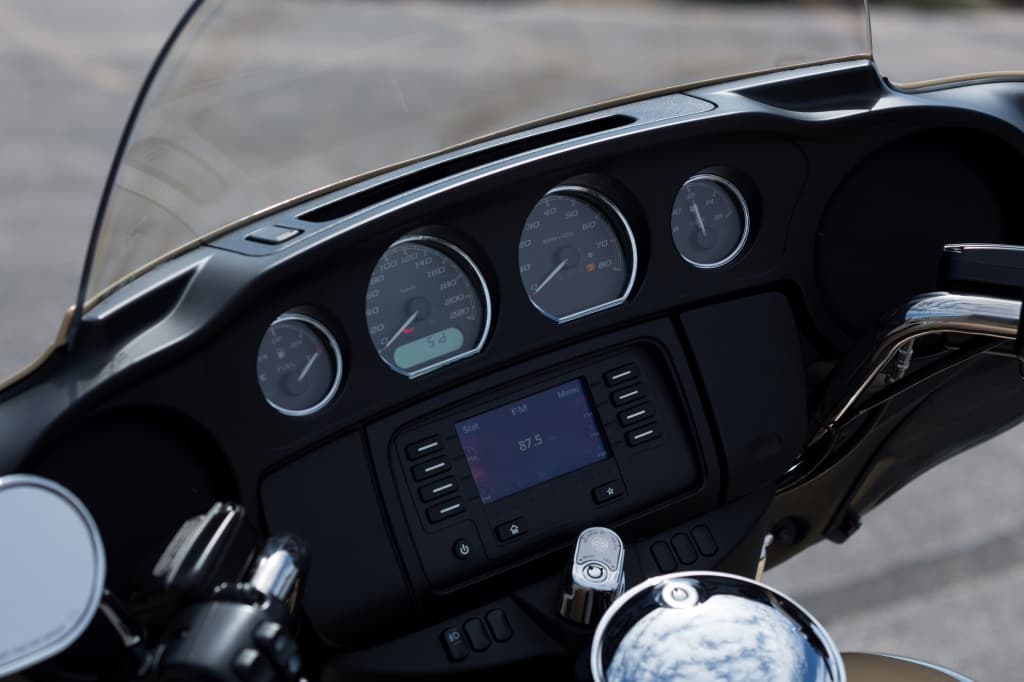 Dettaglio del cruscotto di una moto Harley-Davidson, con strumentazione completa e sistema infotainment digitale per un'esperienza di guida avanzata.