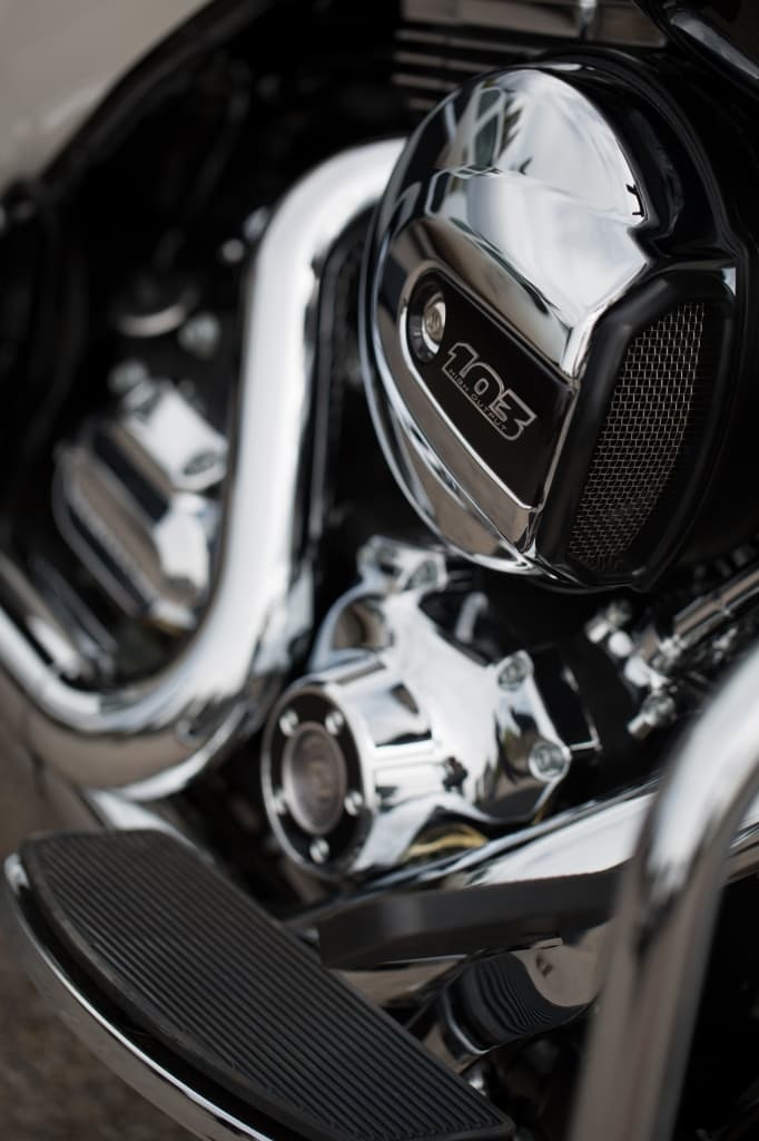 Dettaglio ravvicinato del motore Harley-Davidson Twin Cam 103 High Output con finiture cromate e pedana.