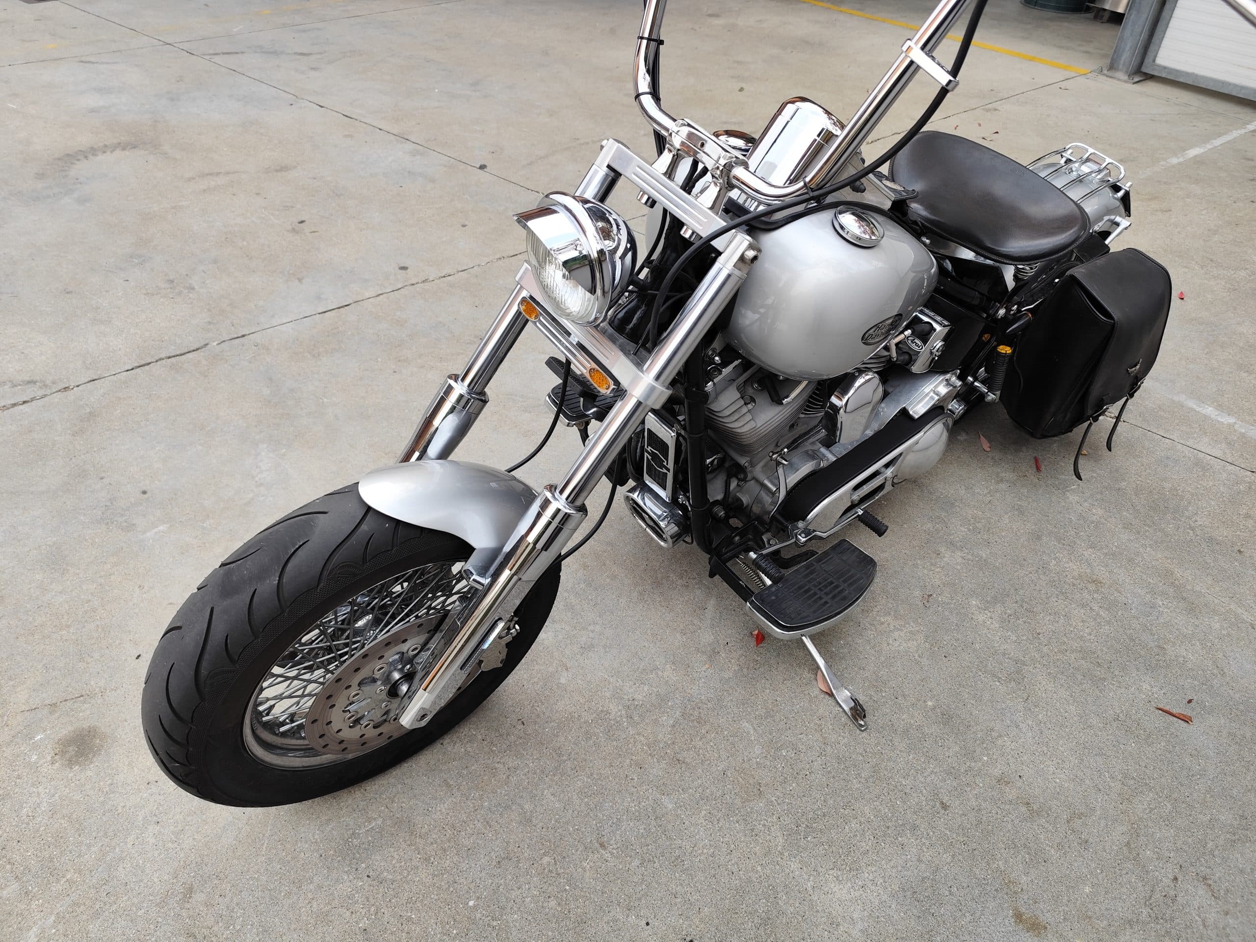 Harley-Davidson cruiser argento, dettagli cromati, motore V-twin, borse in pelle. Perfetta per test ride e avventure su strada.