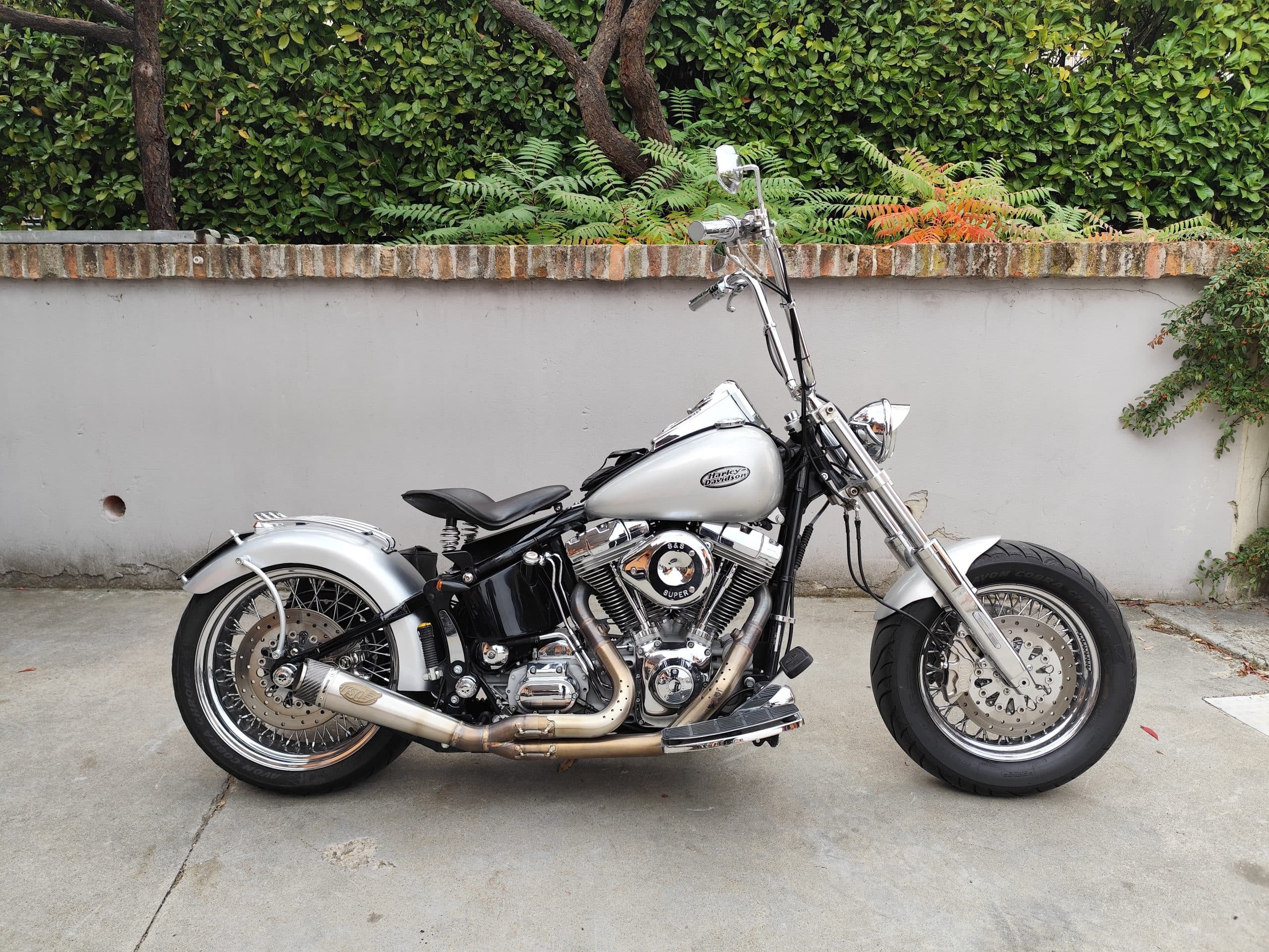 Moto Harley-Davidson customizzata argento, con motore S&S cromato, scarico sportivo e manubrio ape hanger, ideale per test ride.