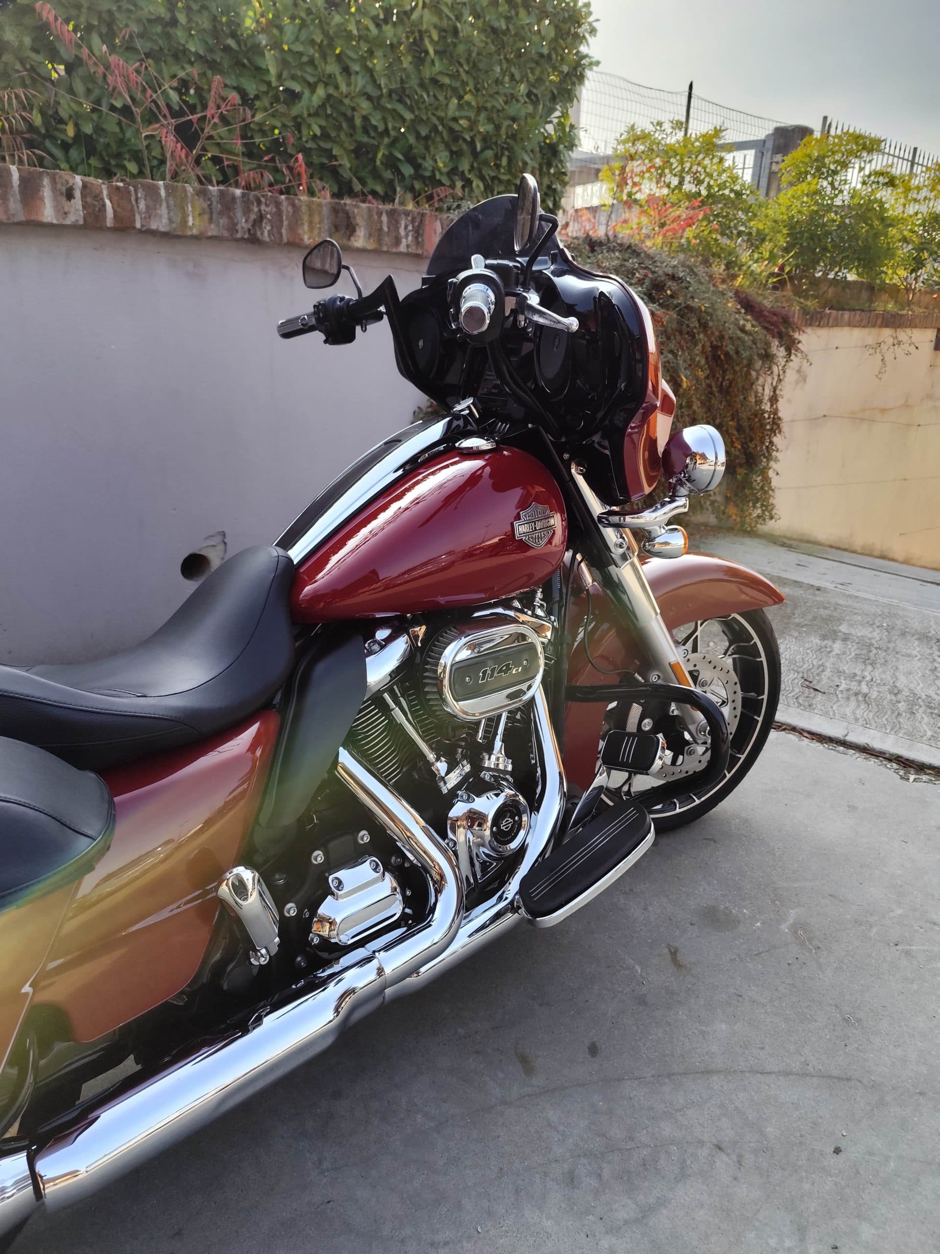 Harley-Davidson touring con motore 114 CI, verniciatura bicolore rosso-bronzo e dettagli cromati, parcheggiata all'aperto.