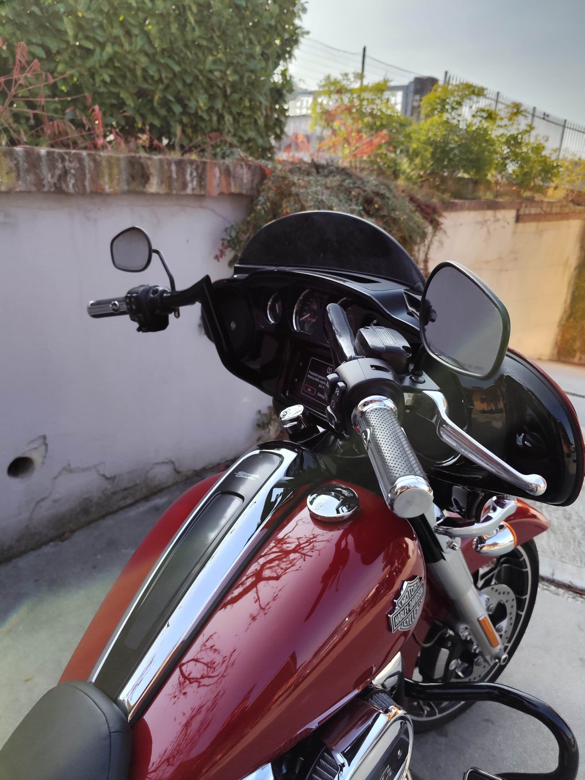 Harley-Davidson rossa lucida, con cupolino nero, manubrio cromato, strumentazione e serbatoio con logo. Dettagli di design.