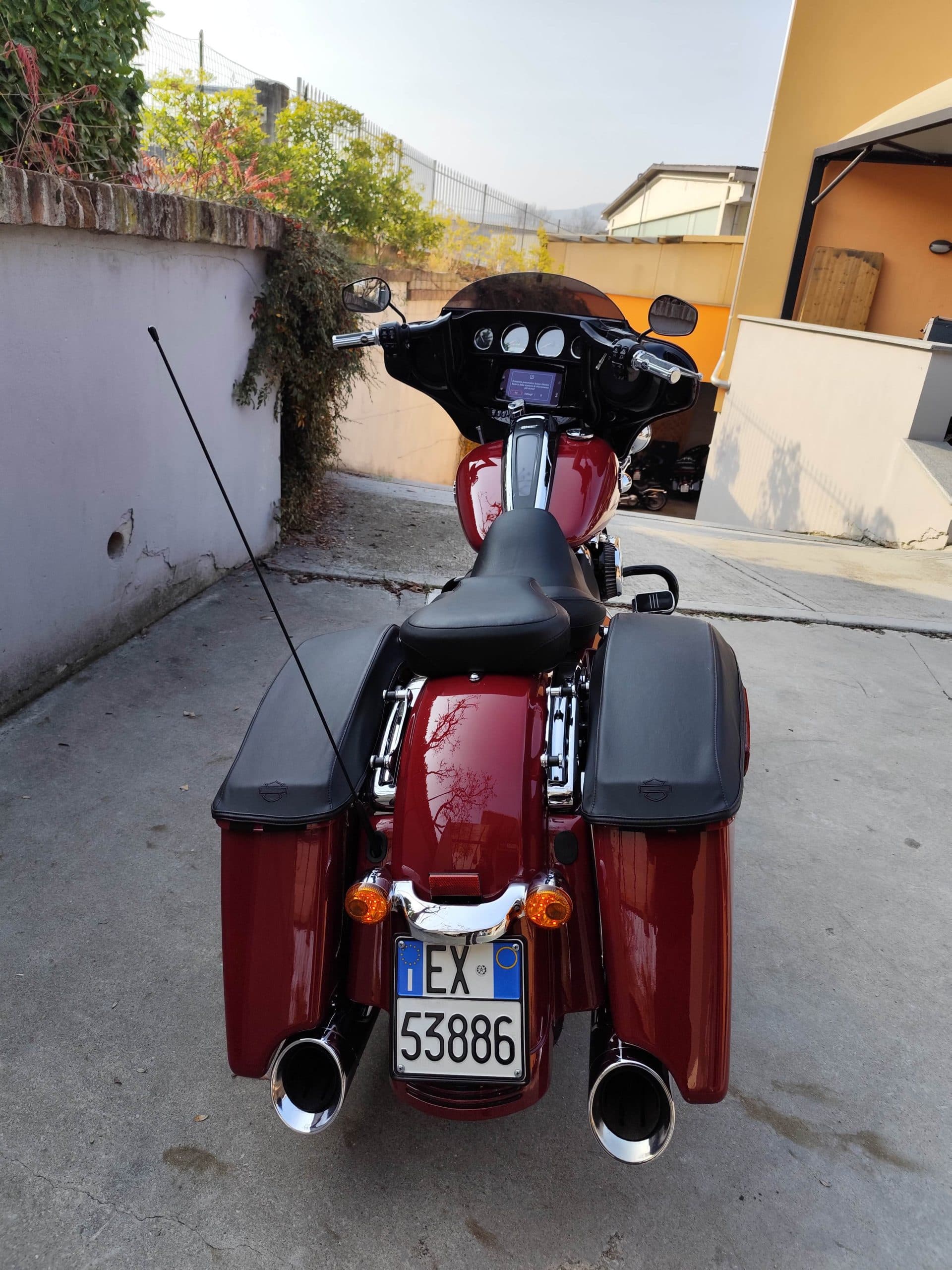 Harley-Davidson touring rossa, vista posteriore. Evidenti targa italiana EX 53886, doppio scarico e borse laterali. Dettagli dei motori.