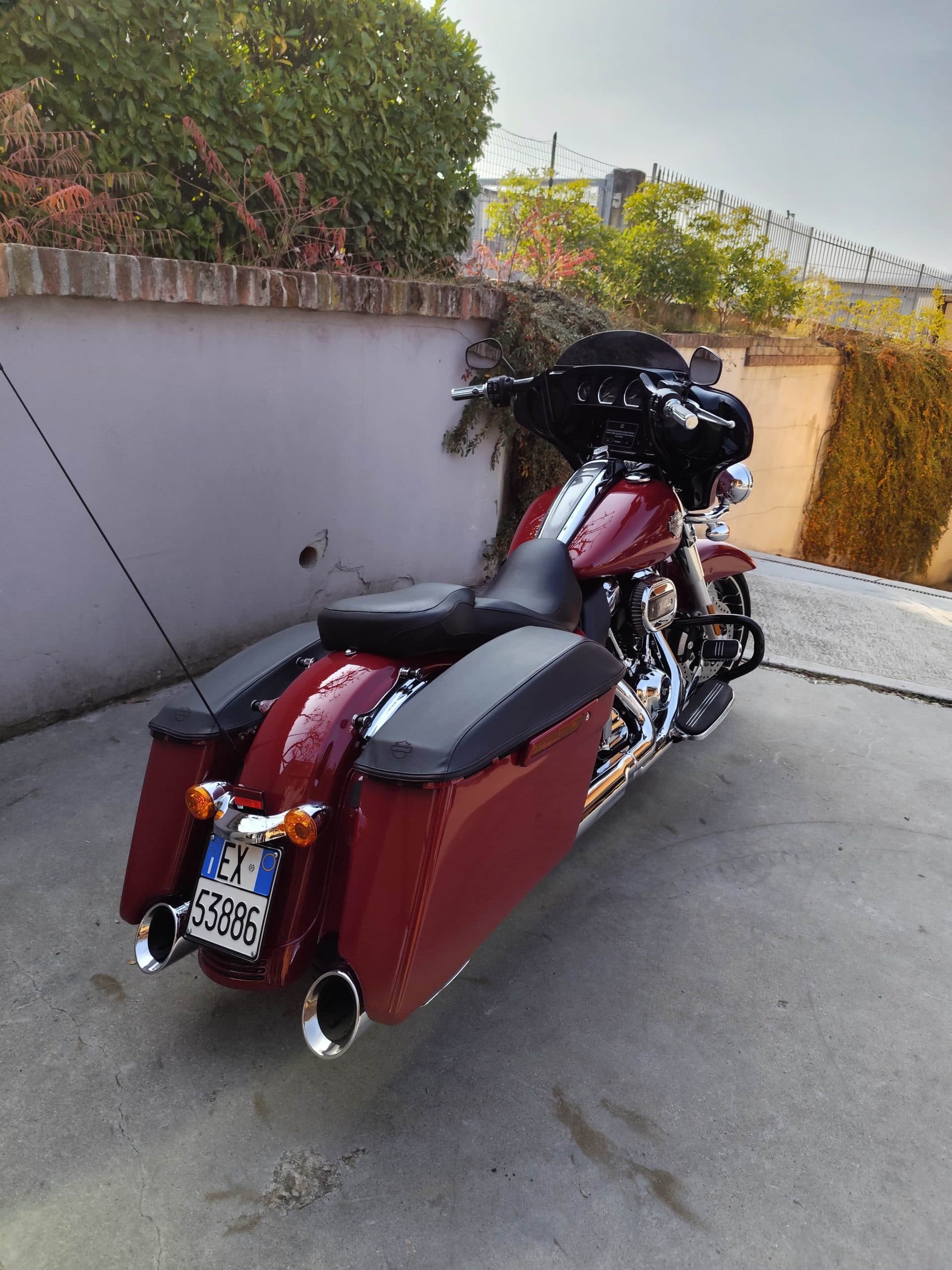 Harley-Davidson touring rossa parcheggiata, vista posteriore destra con borse laterali, scarichi cromati e targa italiana EX 53886.