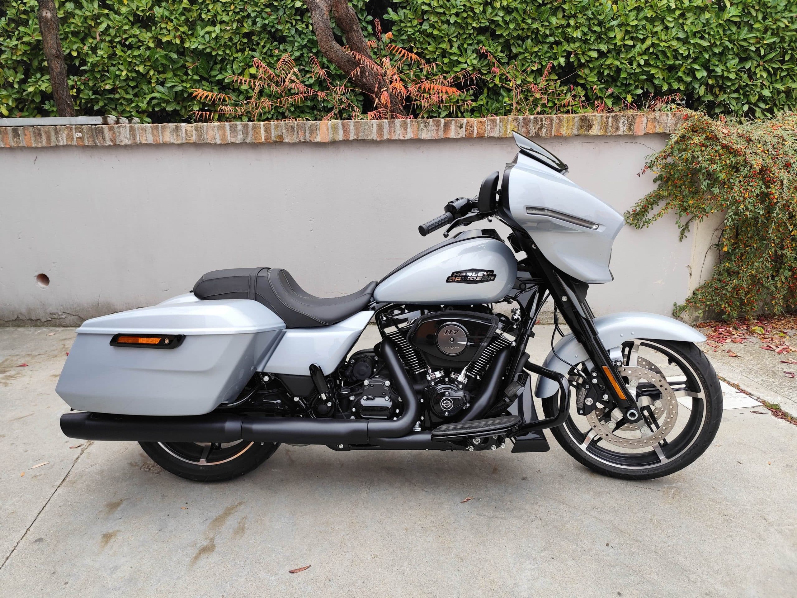 Harley-Davidson touring grigio chiaro con motore Milwaukee-Eight 117, scarichi neri e cerchi custom, parcheggiata.