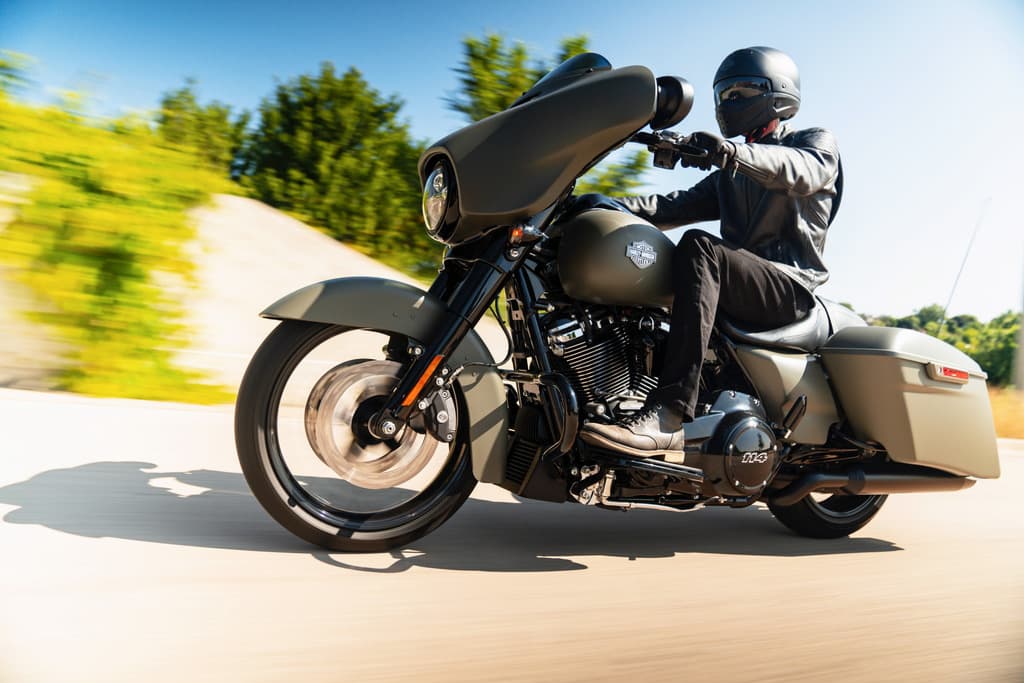 Motociclista in sella a una Harley-Davidson Street Glide Special 114 verde opaco, con abbigliamento tecnico, in movimento su strada.