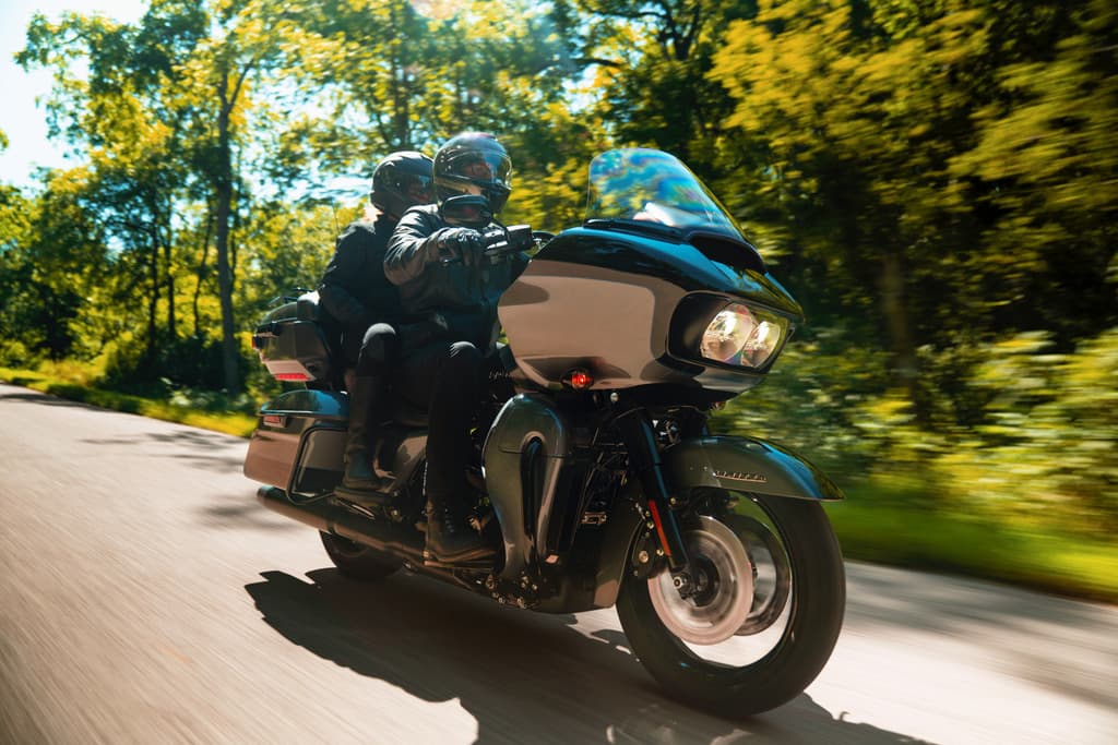 Due motociclisti con abbigliamento tecnico su Harley-Davidson touring in movimento su strada panoramica. Perfetta per test ride.