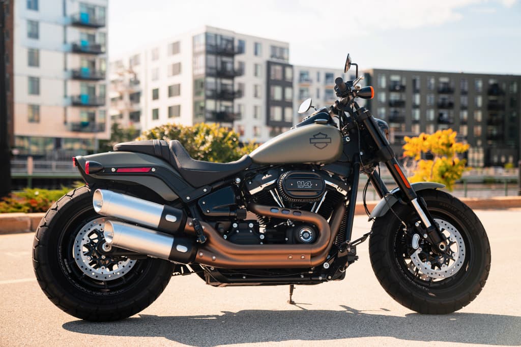 Harley-Davidson Fat Bob 114 color verde oliva opaco, con motore Milwaukee-Eight 114 e scarichi bronzo, parcheggiata in ambiente urbano.