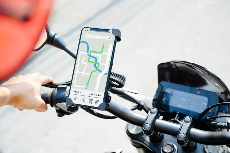 Motociclista con casco rosso visualizza un percorso di 50.5 km e 1 ora e 30 minuti su navigatore GPS montato sul manubrio della