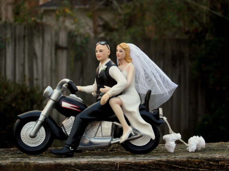 Topper nuziale personalizzato con sposi su moto Harley-Davidson, sposo in gilet e sposa in abito bianco con velo, simbolo di passione e avventura.