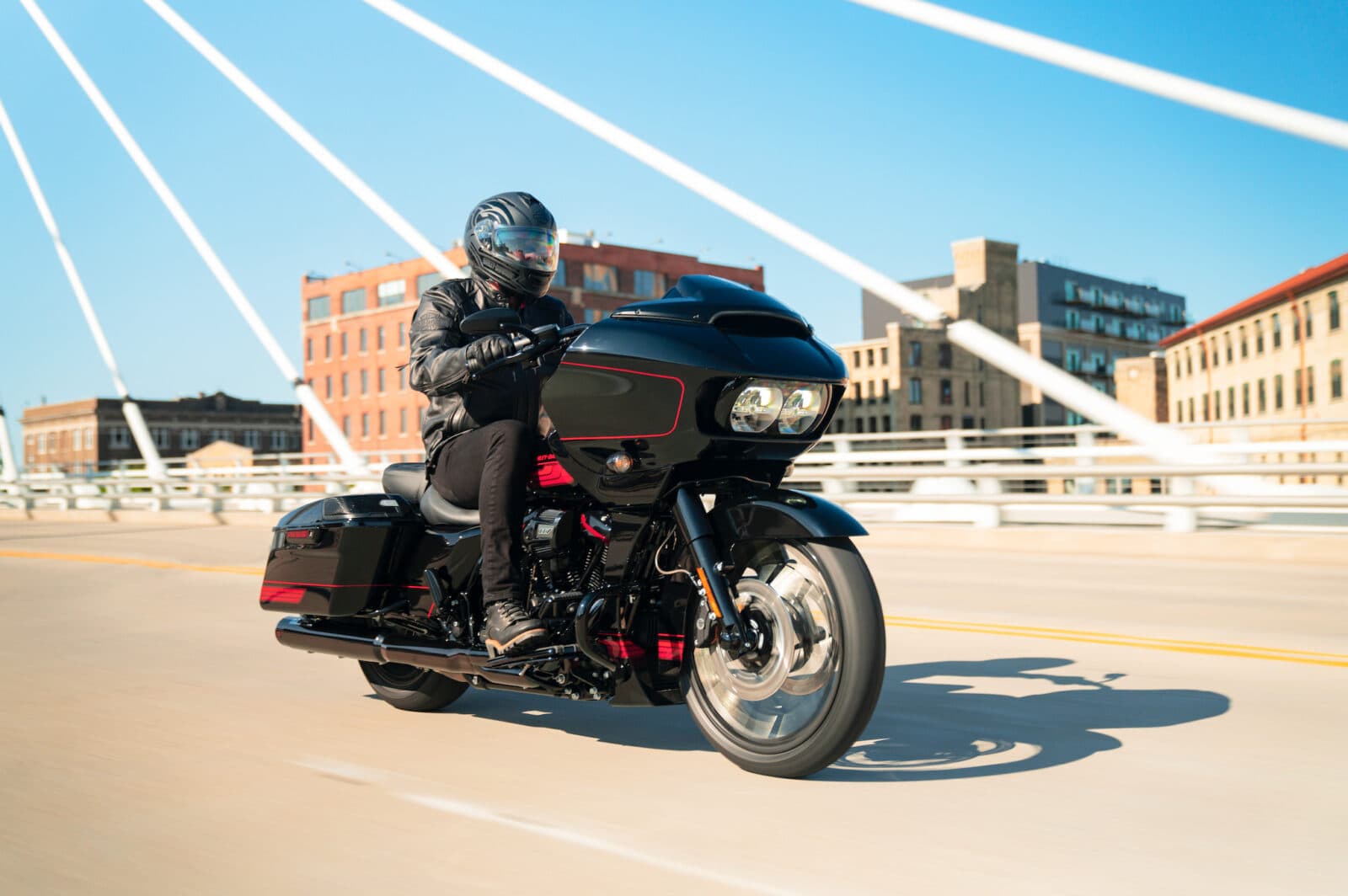 Motociclista in abbigliamento tecnico su Harley-Davidson nera con dettagli rossi, in movimento su un ponte. Perfetta per un test ride.