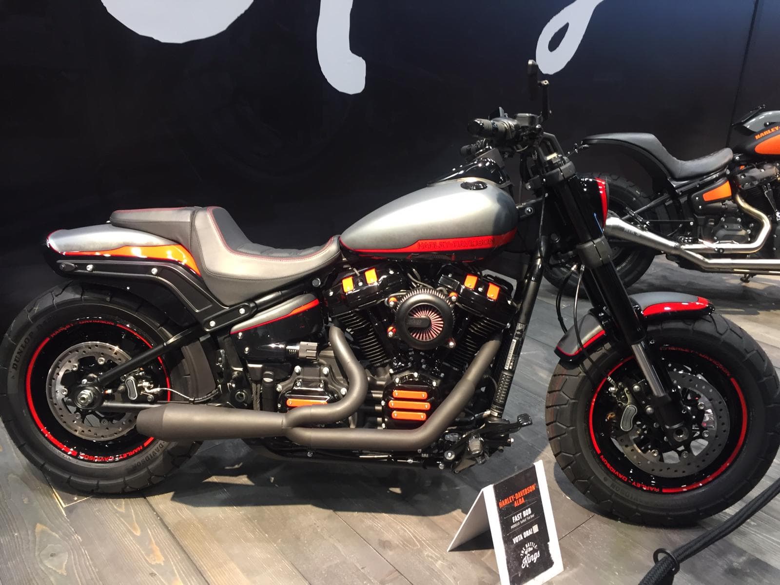 Moto Harley-Davidson Fast Bob customizzata, colorazione grigio opaco e nero con accenti arancioni/rossi, esposta ad Alba.