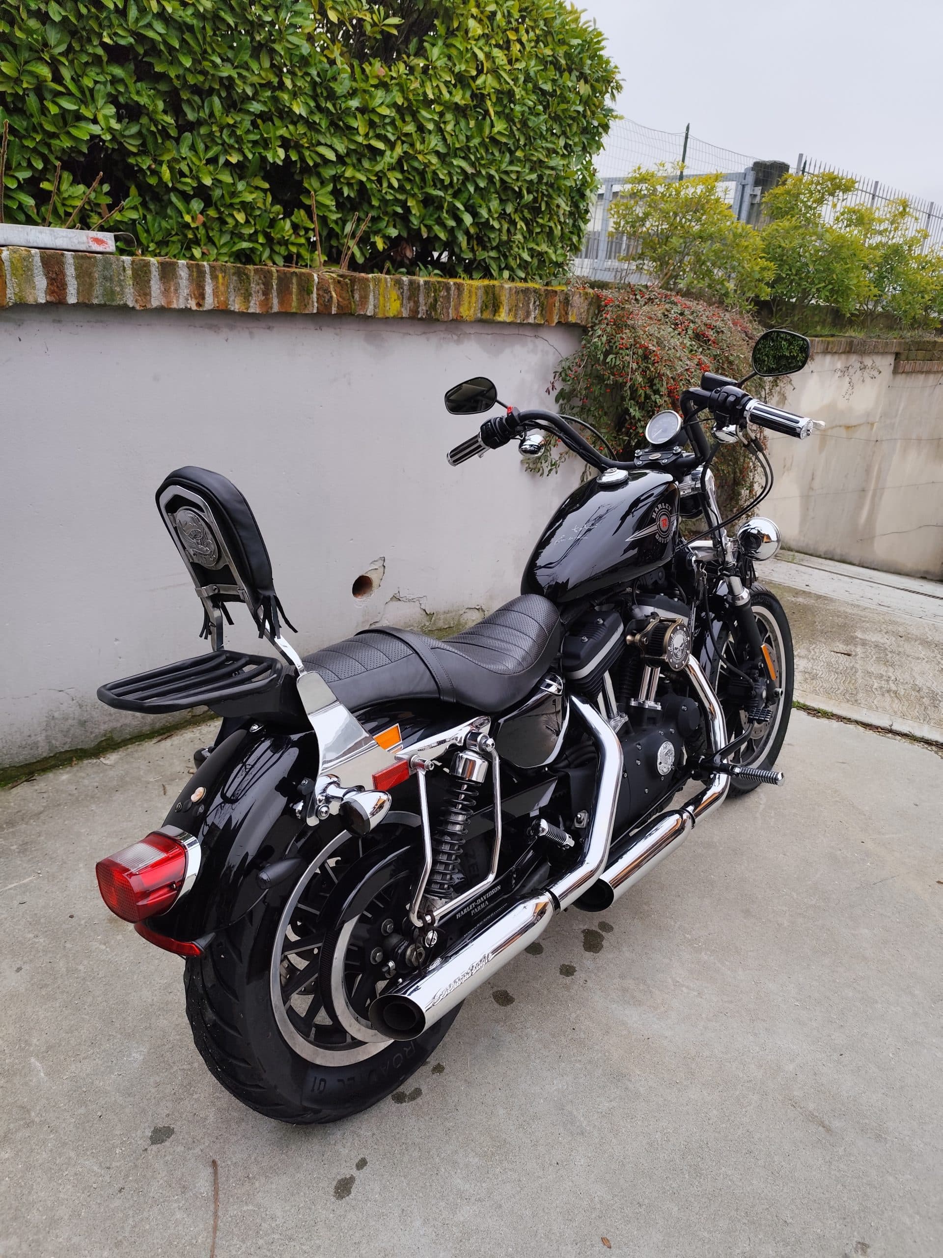 Harley-Davidson nera custom con scarichi cromati, sissy bar, portapacchi e dettagli motore. Perfetta per un test ride.