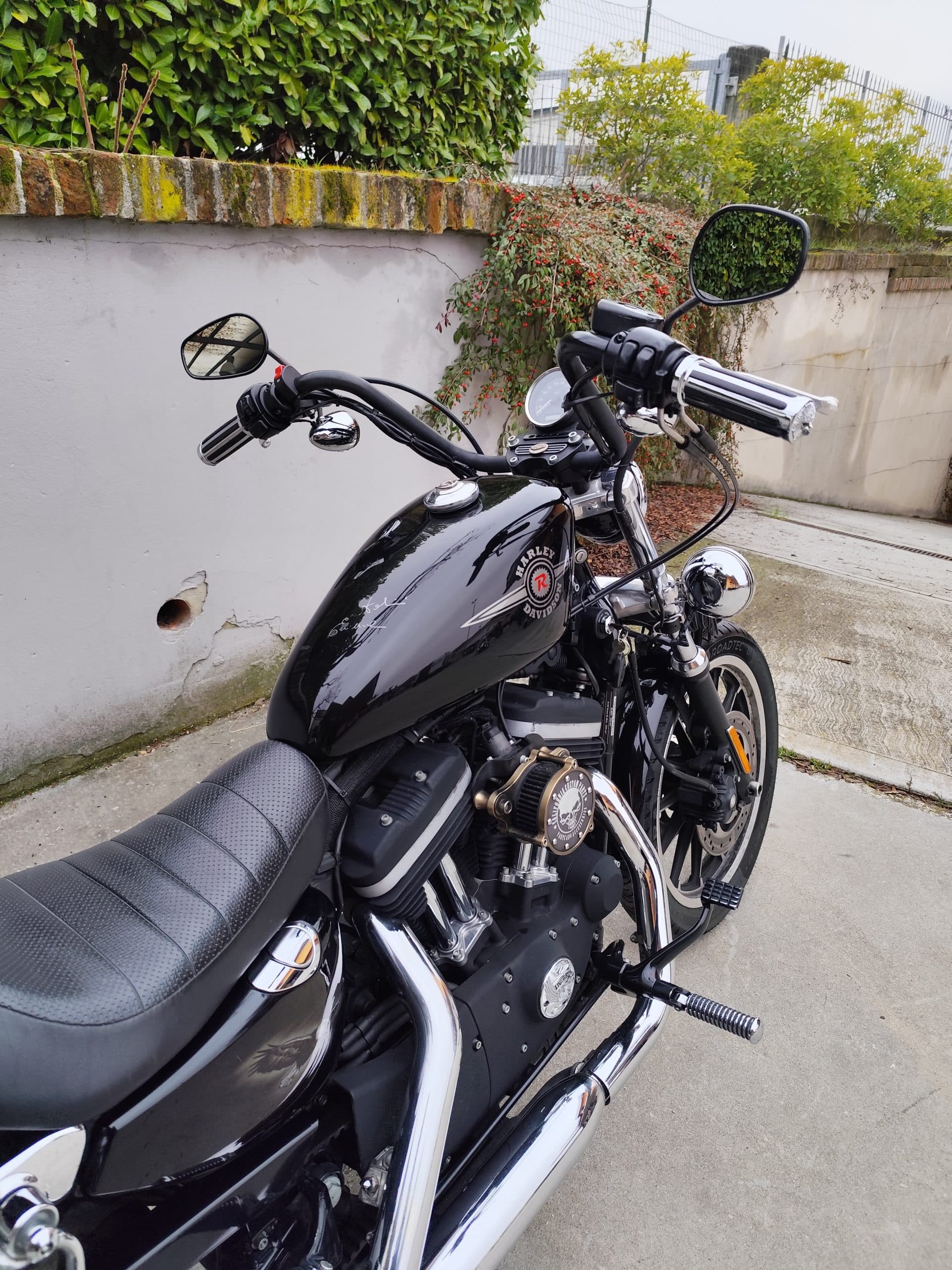 Harley-Davidson Sportster nera parcheggiata, con dettagli del motore, scarichi cromati, serbatoio lucido con logo e manubrio. Ideale per test ride.