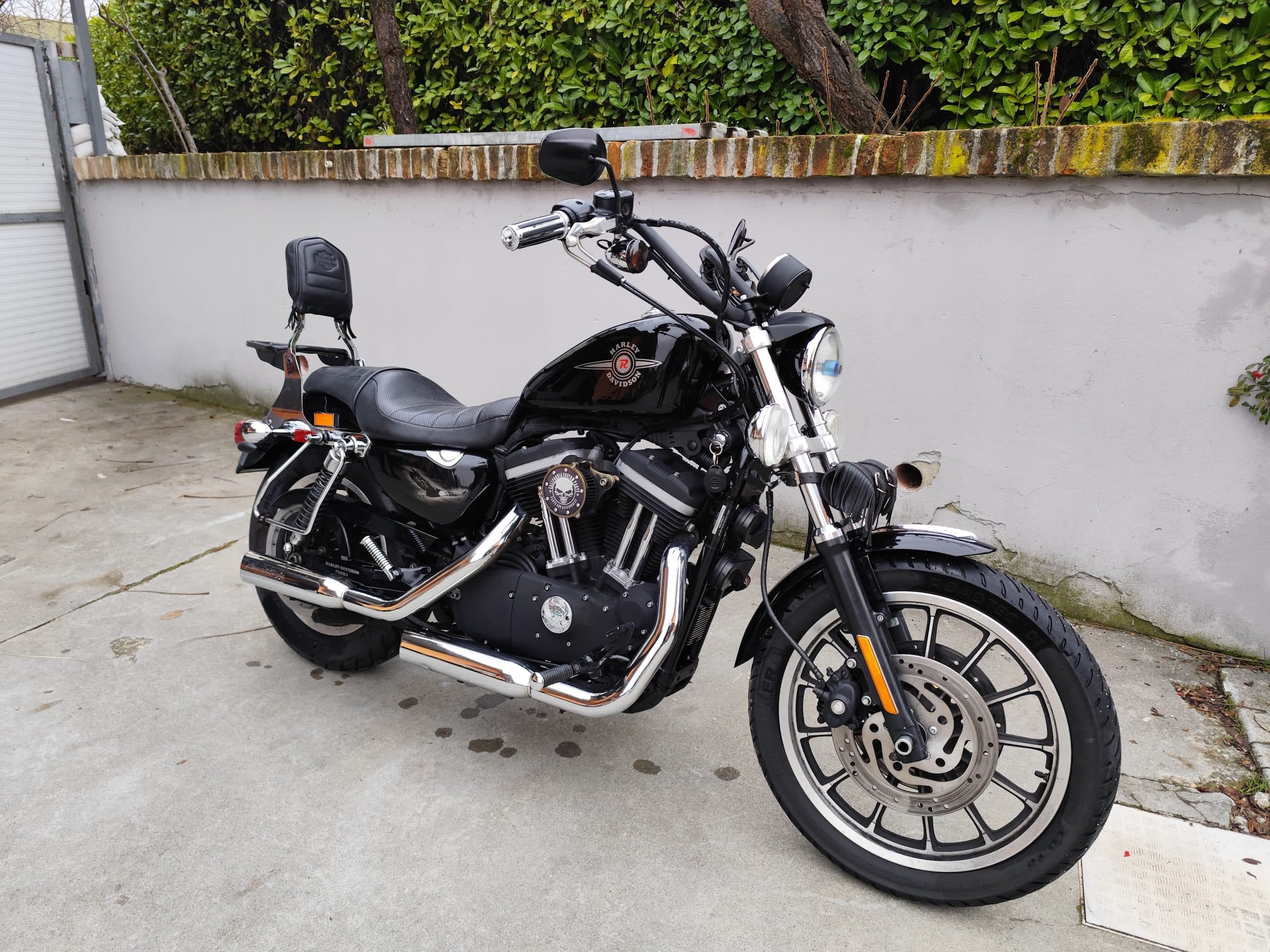 Harley-Davidson Sportster nera, con motore Evolution, scarichi cromati, emblema teschio e cerchi in lega, parcheggiata all'aperto.