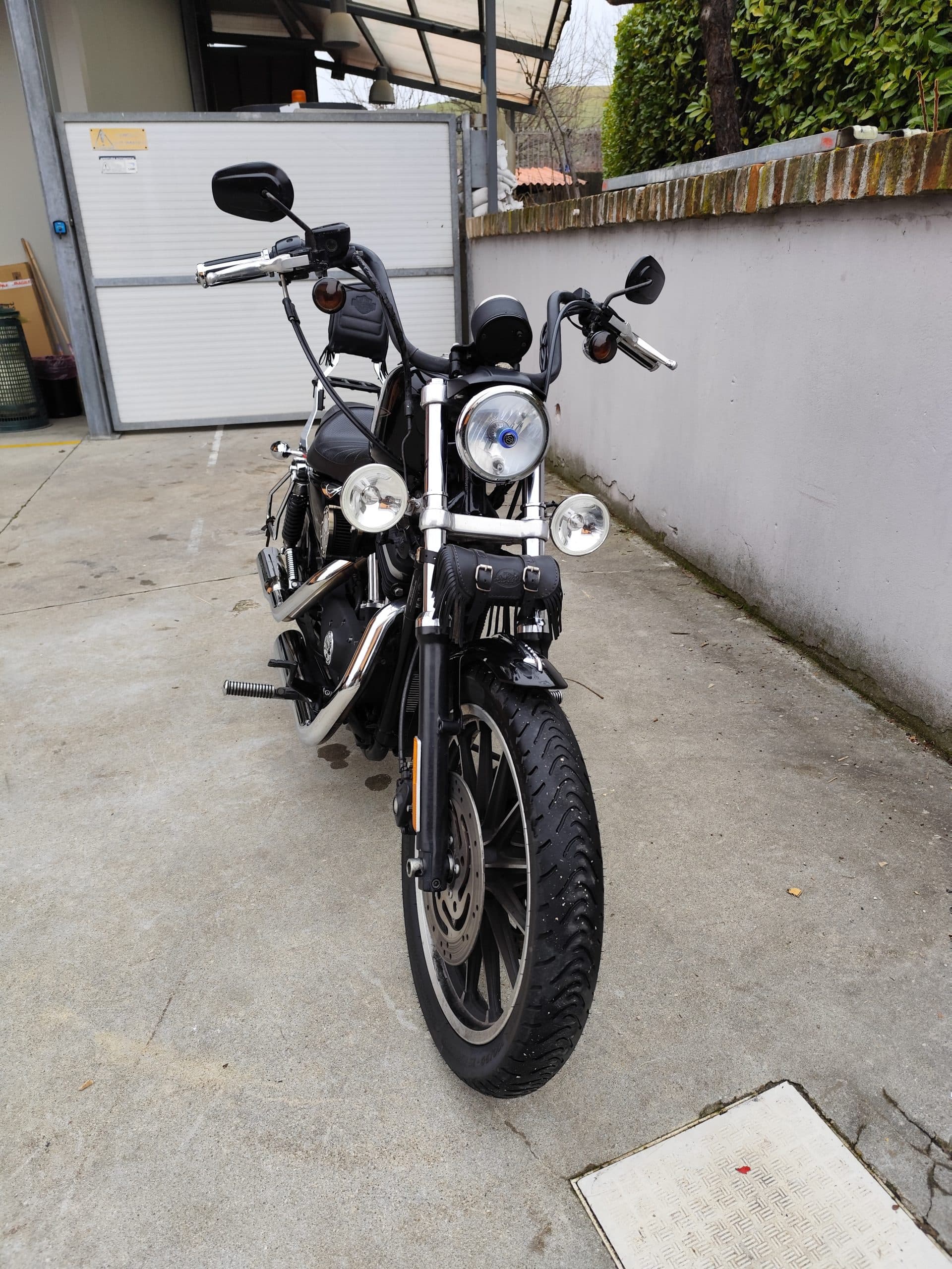 Harley-Davidson Sportster nera con manubrio custom, fari ausiliari e dettagli cromati, parcheggiata su piazzale. Disponibile per test ride.