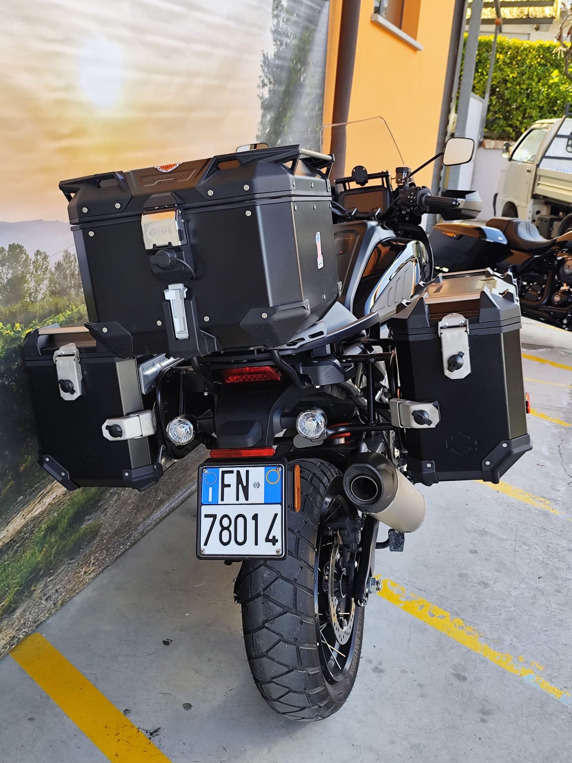 Vista posteriore di una moto Harley-Davidson Pan America nera, equipaggiata con bauletto e valigie laterali Givi Outback Evo. Targa italiana FN 78014.