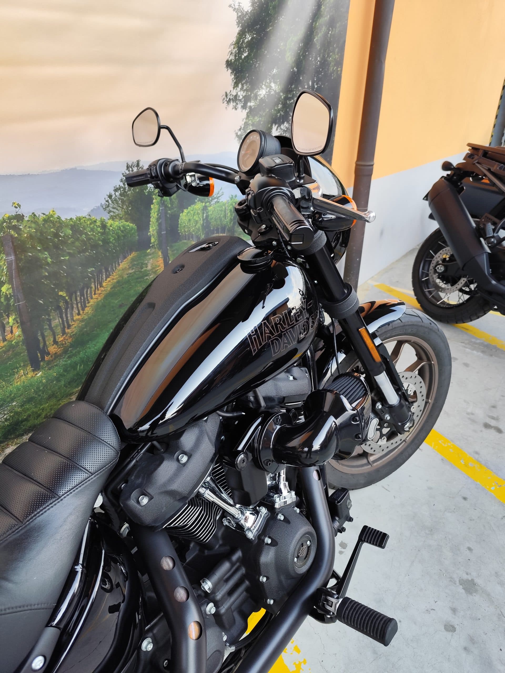 Harley-Davidson nera con serbatoio lucido e logo, motore Revolution Max a vista, scarico nero opaco. Esposta in concessionaria con sfondo murale vign