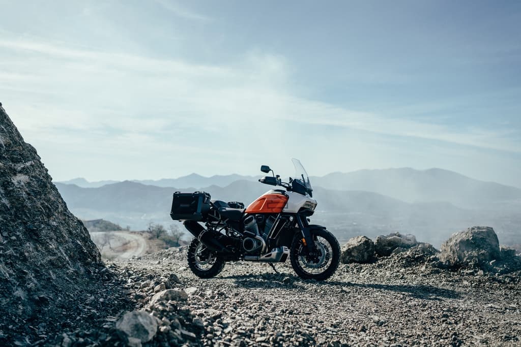 Harley-Davidson Pan America, moto adventure con borse laterali, su sterrato montano. Scopri i motori e prenota un test ride.