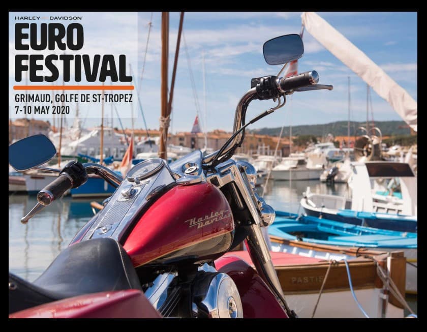 Promozione Harley-Davidson Euro Festival 2020 a Grimaud: moto rossa in primo piano con manubrio cromato, sullo sfondo porto turistico.