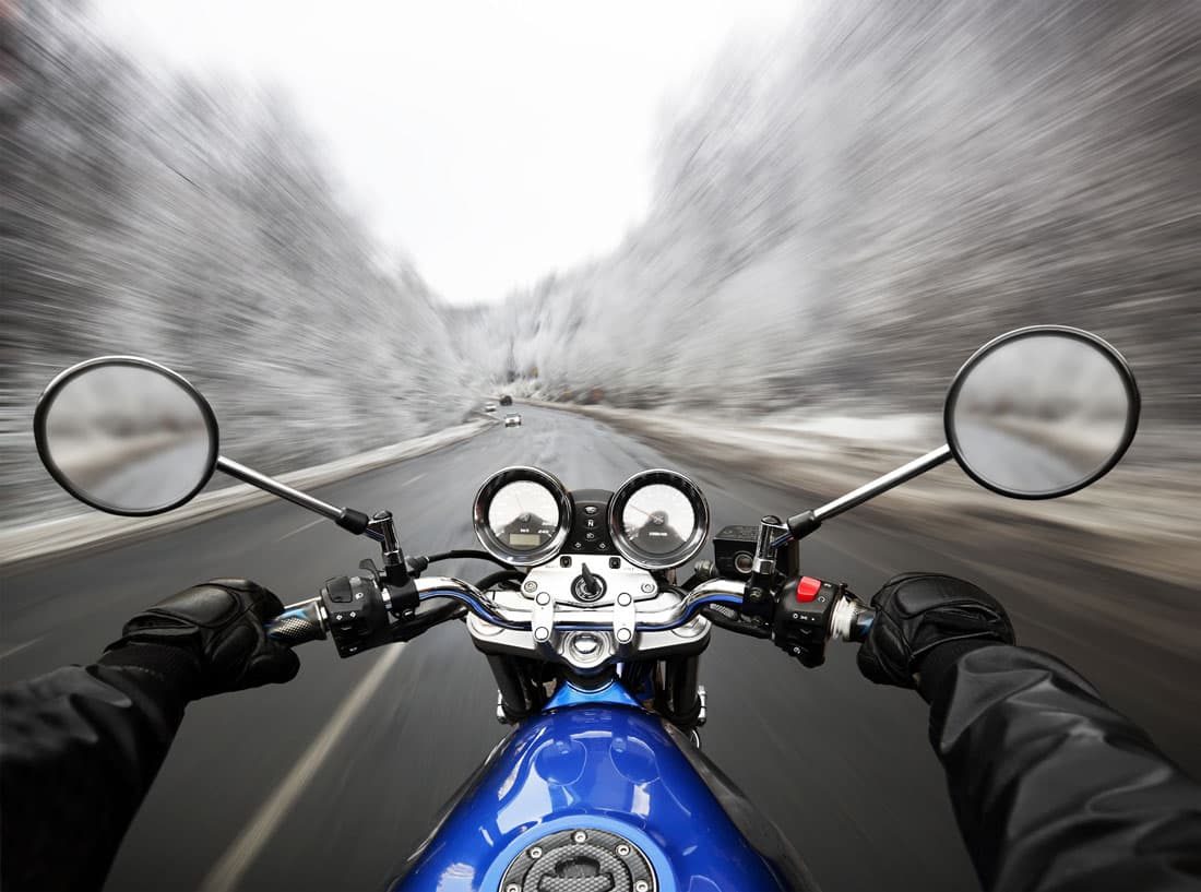 Guida dinamica in moto: prospettiva del pilota su strada panoramica, con abbigliamento tecnico e la potenza dei motori.
