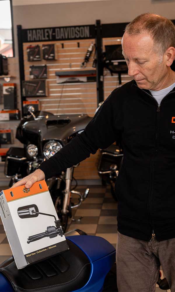 Cliente o addetto Harley-Davidson esamina una scatola di specchietti Wild One Collection per moto in una concessionaria.