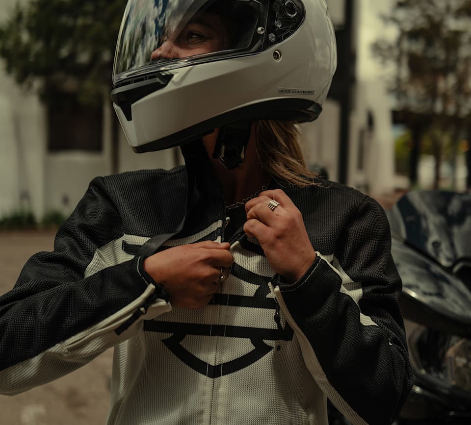 Motociclista con casco integrale bianco e giacca tecnica protettiva Harley-Davidson nera e bianca, si prepara per un test ride.