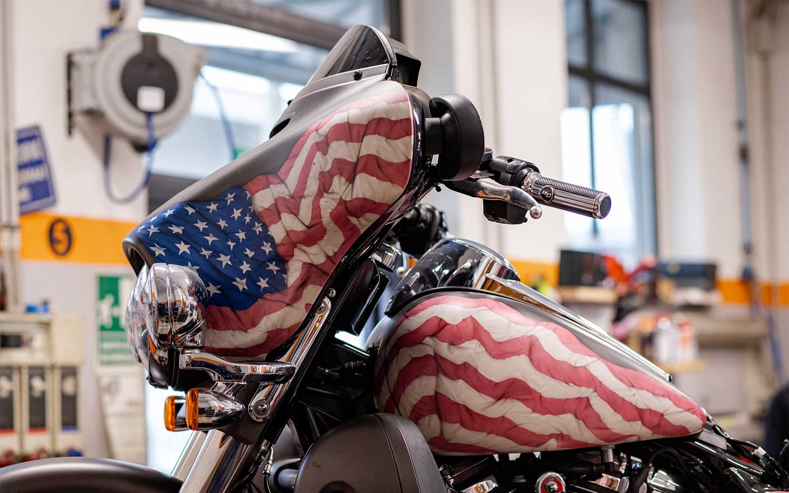 Harley-Davidson customizzata con bandiera USA Harley-Davidson customizzata con verniciatura artistica raffigurante bandiera americana su carenatura e serbatoio, in officina.
