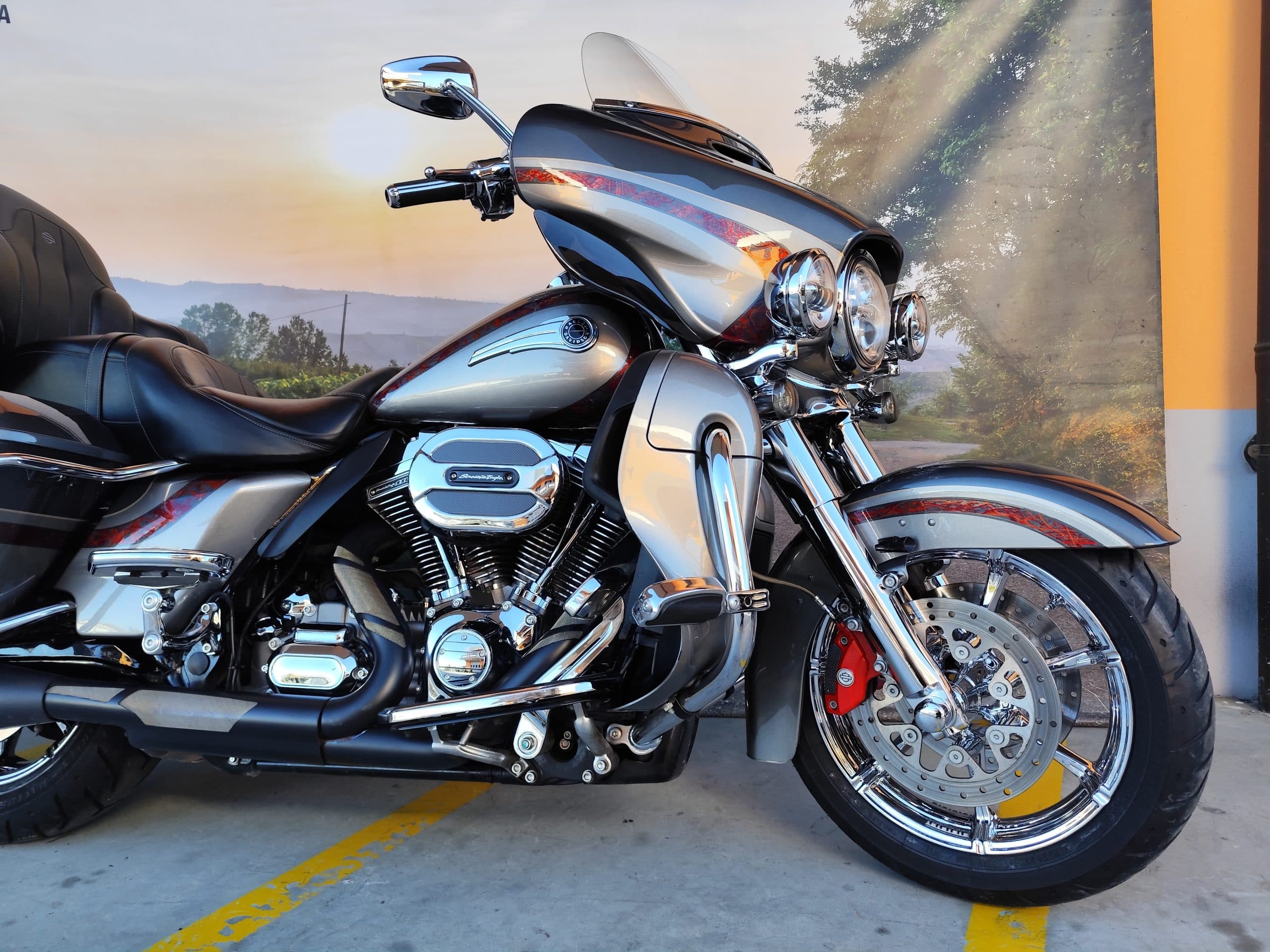IMG_20260217_091354.jpg Harley-Davidson touring customizzata, colorazione argento e grigio con dettagli rossi, motore V-Twin cromato, fari a LED e pinze freno rosse.
