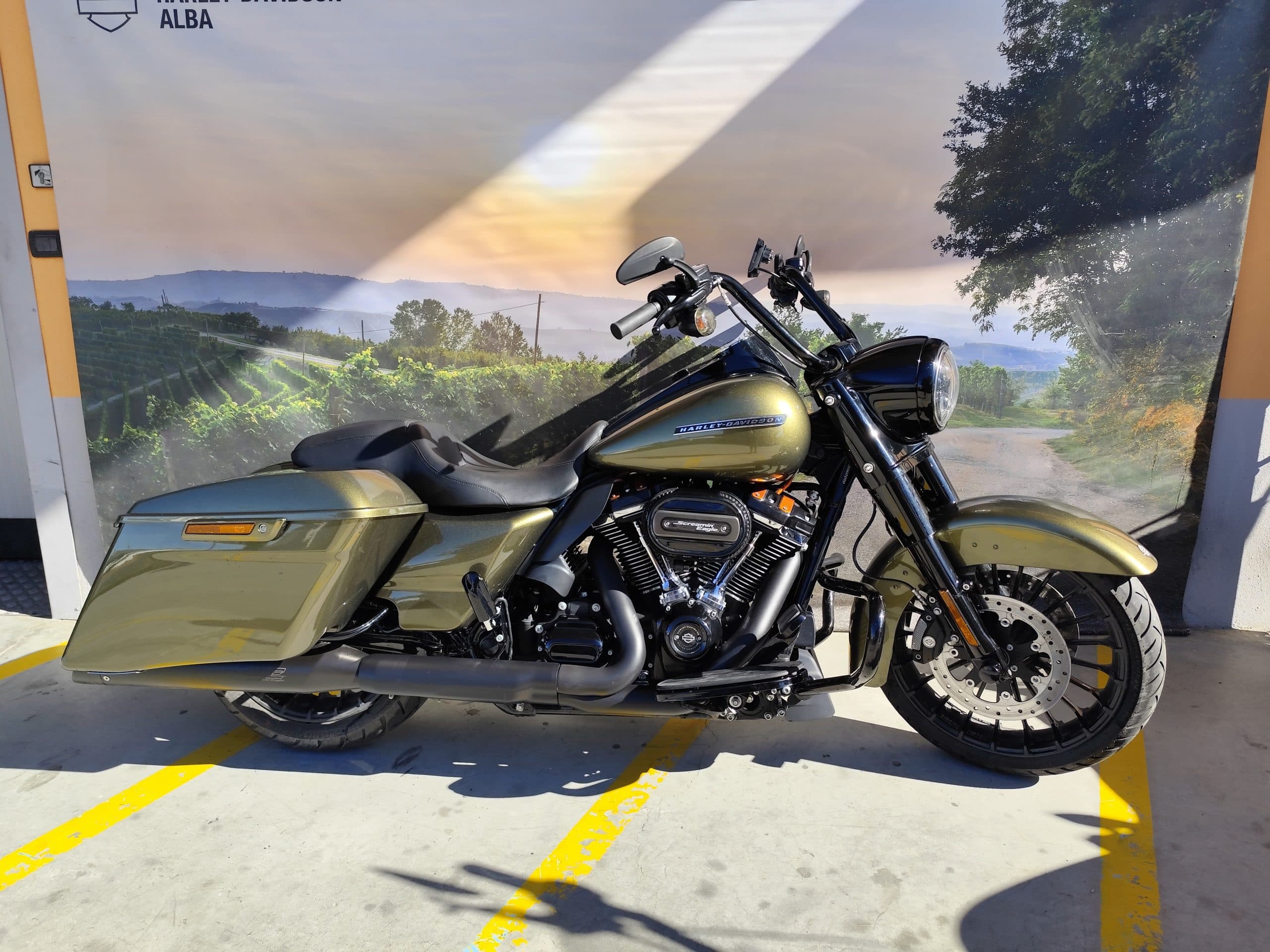 IMG_20260217_122024-scaled Moto Harley-Davidson touring verde metallizzato, motore Screamin' Eagle, esposta presso la concessionaria di Alba su sfondo collinare.