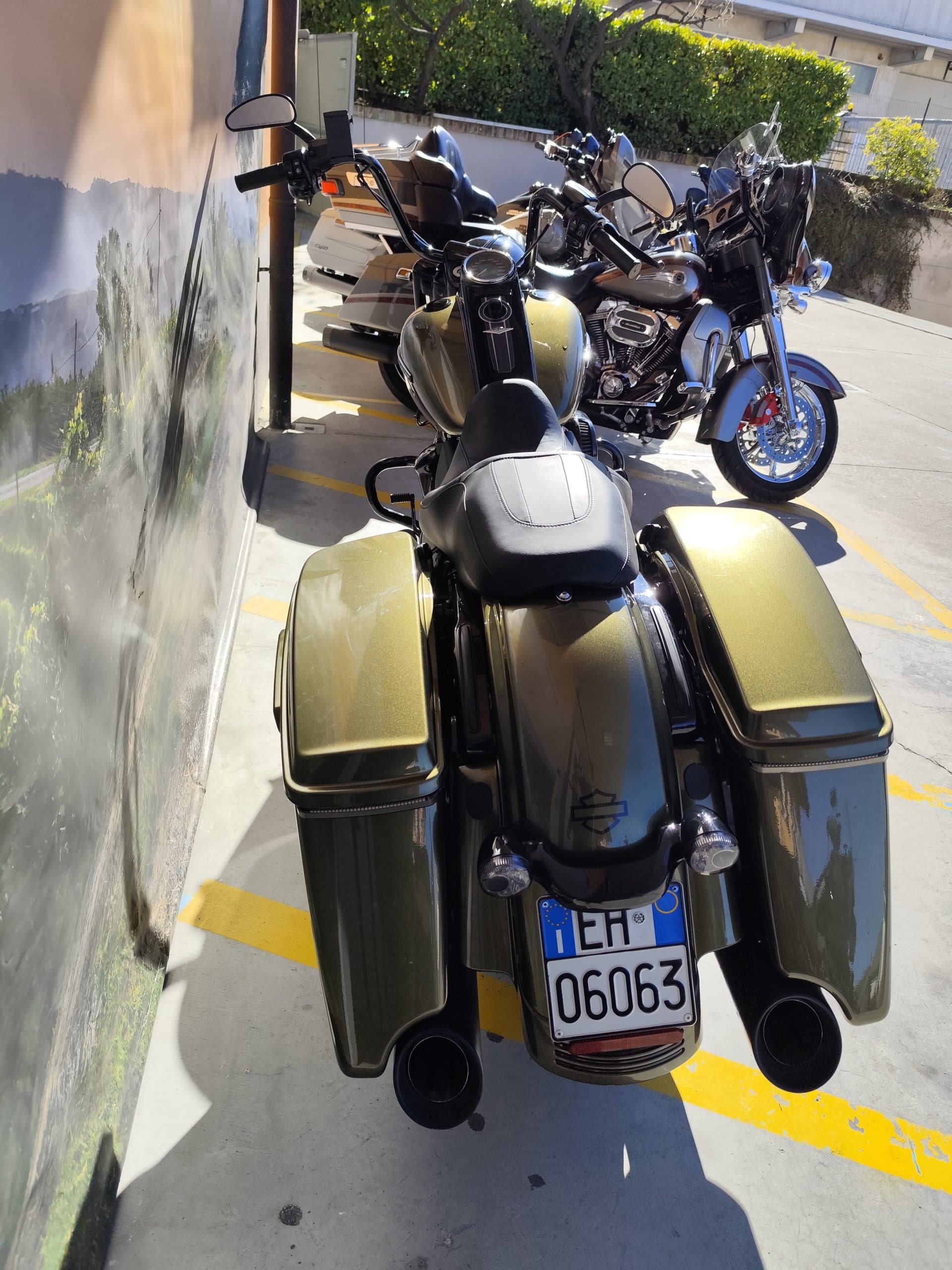 IMG_20260217_122042.jpg Harley-Davidson touring verde metallizzato con borse laterali e scarichi neri, affiancata da un modello touring grigio-argento.