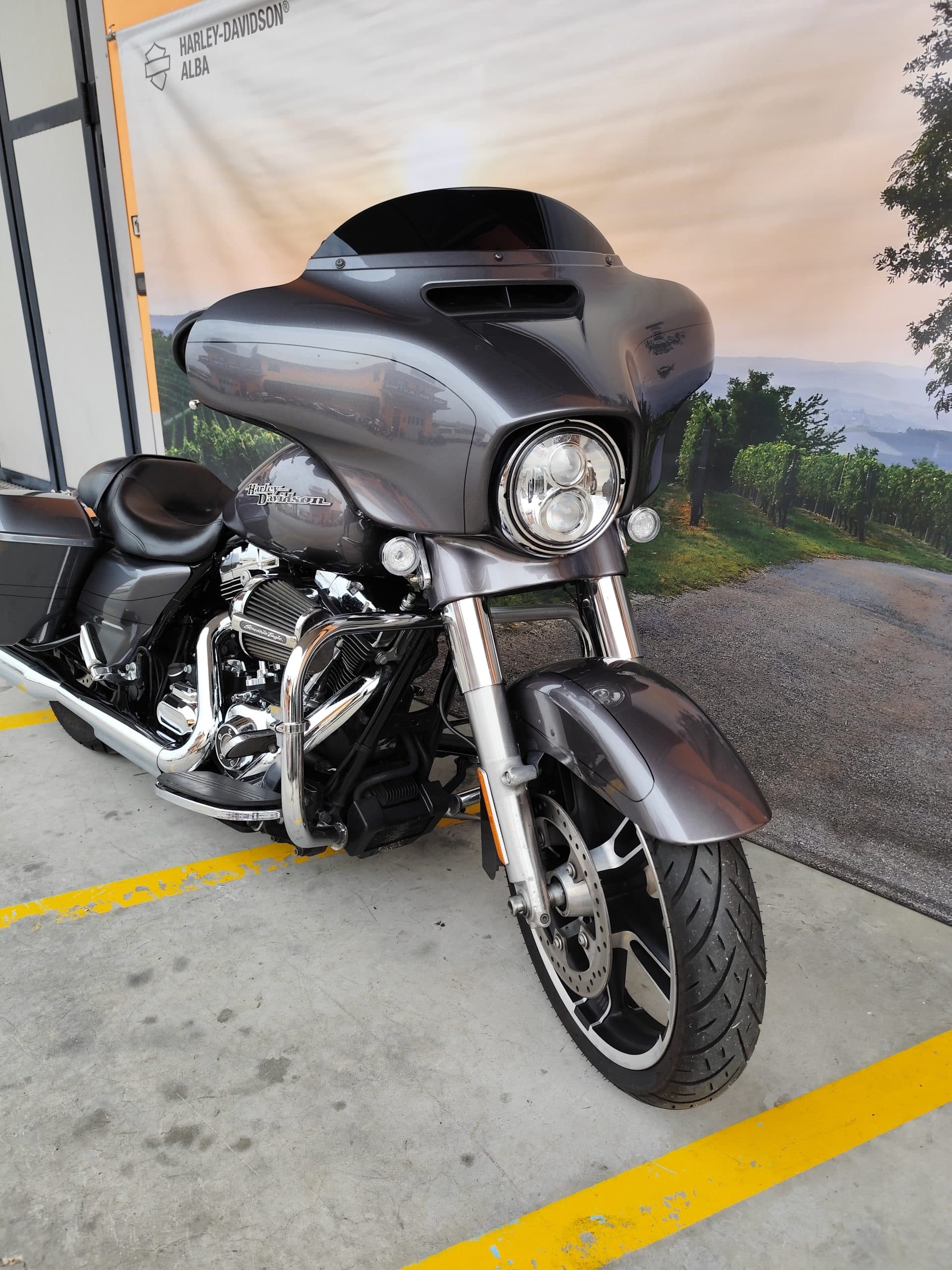 IMG_20260227_085439.jpg Moto Harley-Davidson touring grigia, con motore cromato e faro LED, esposta presso la concessionaria Harley-Davidson Alba.
