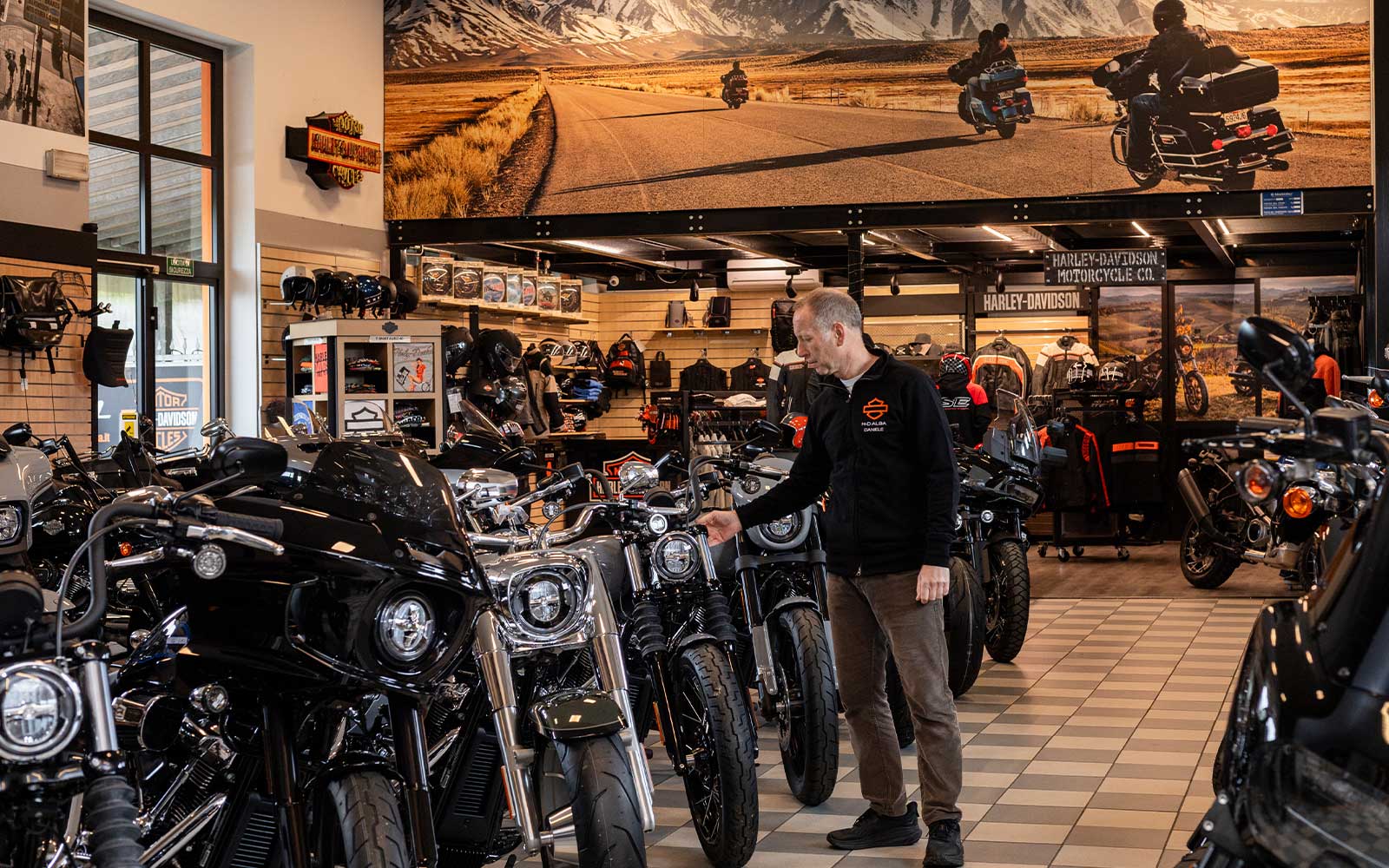 Showroom Harley-Davidson Alba: scopri le nostre moto Interno di una concessionaria Harley-Davidson ad Alba, con esposizione di numerosi modelli di moto, abbigliamento e accessori. Un uomo osserva le motociclette.