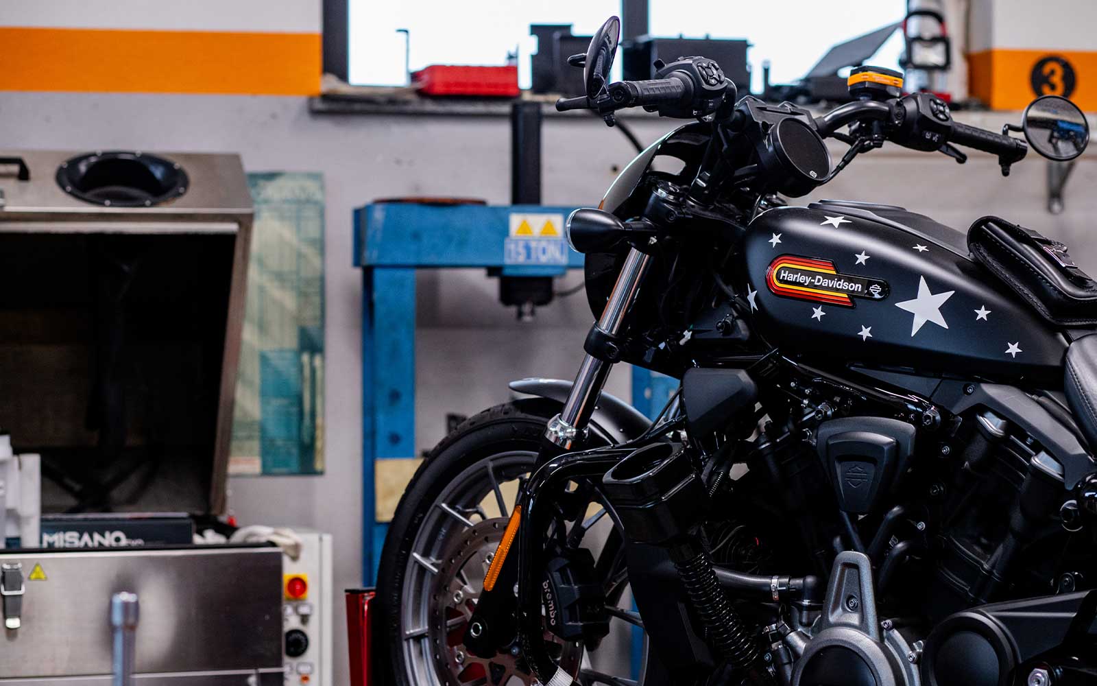 Harley-Davidson customizzata con stelle in officina Harley-Davidson con serbatoio customizzato a stelle e logo distintivo, in officina. Dettagli su motore, forcella e impianto frenante Brembo.