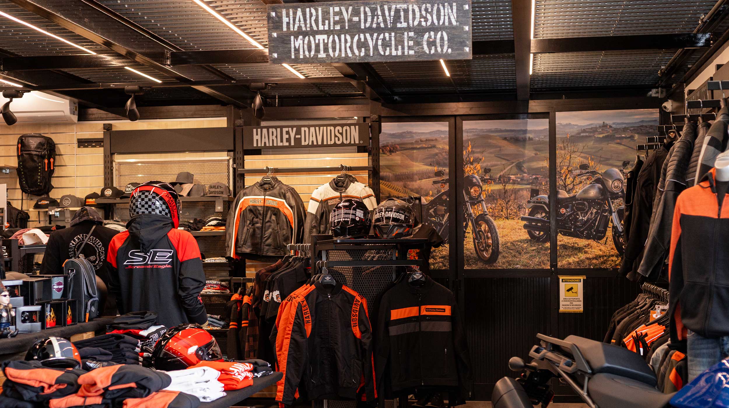 Abbigliamento e accessori originali Harley-Davidson in esposizione. Esposizione di abbigliamento e accessori originali Harley-Davidson in concessionaria. Giubbotti, caschi e merchandising con logo, sullo sfondo moto.