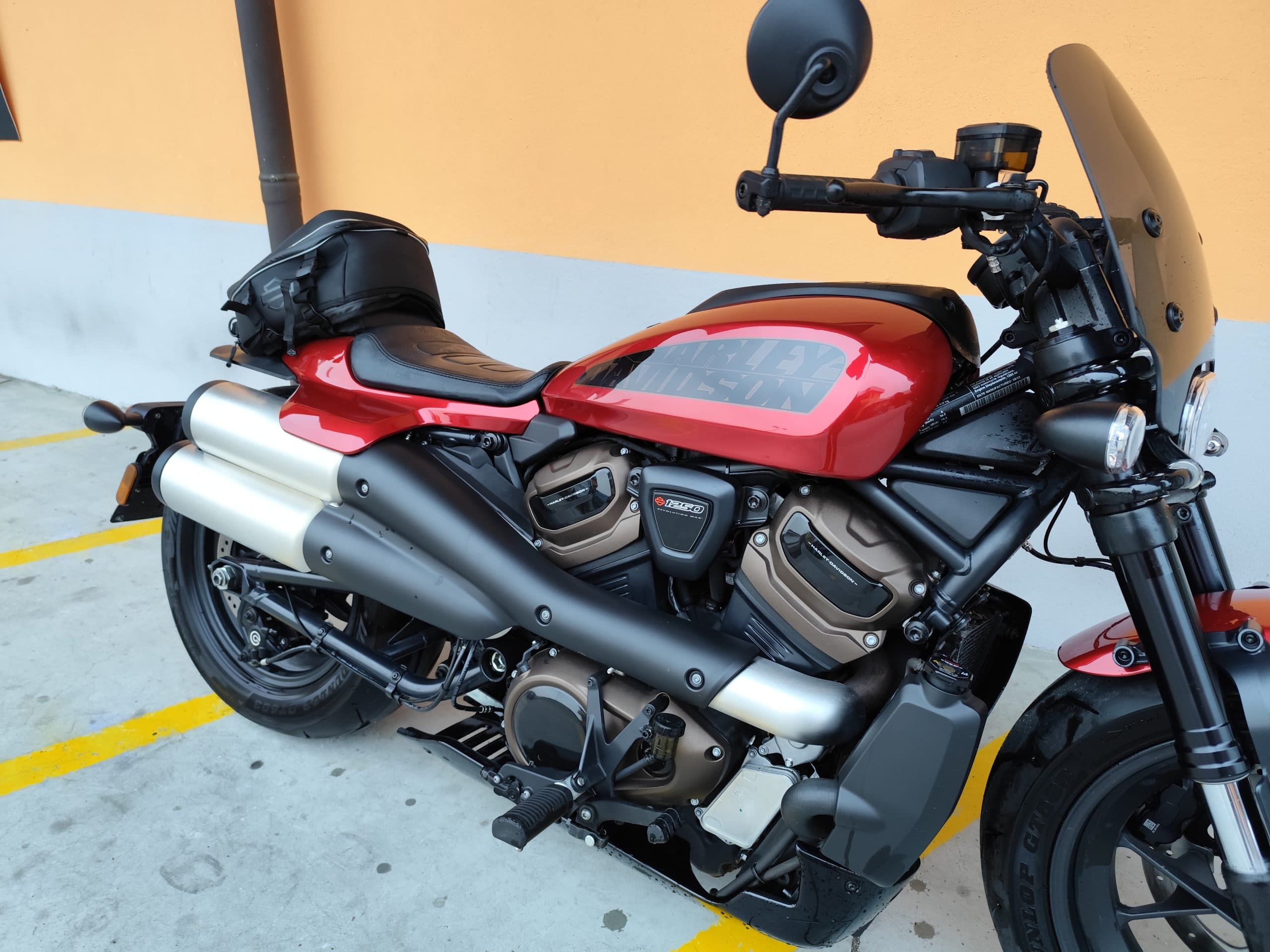 Harley-Davidson Sportster S rossa Harley-Davidson Sportster S rossa parcheggiata, con motore Revolution Max 1250, scarico alto, cupolino e borsa posteriore. Dettagli del motore e della carrozzeria lucida.