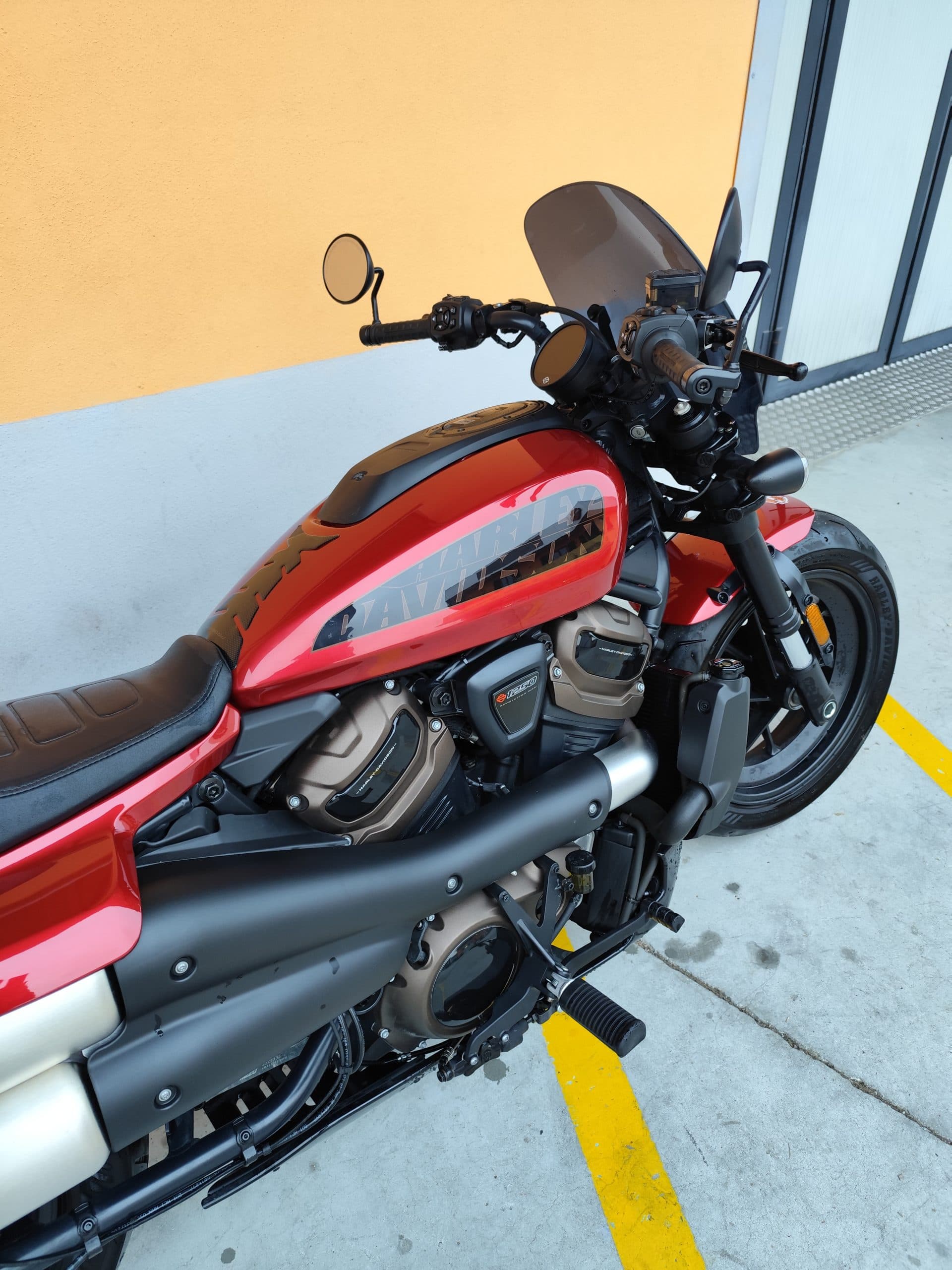 Harley-Davidson Sportster S rossa – Concessionaria Alba Harley-Davidson Sportster S rossa parcheggiata all'aperto. Dettaglio del motore Revolution Max 1250T, scarico, serbatoio e manubrio.