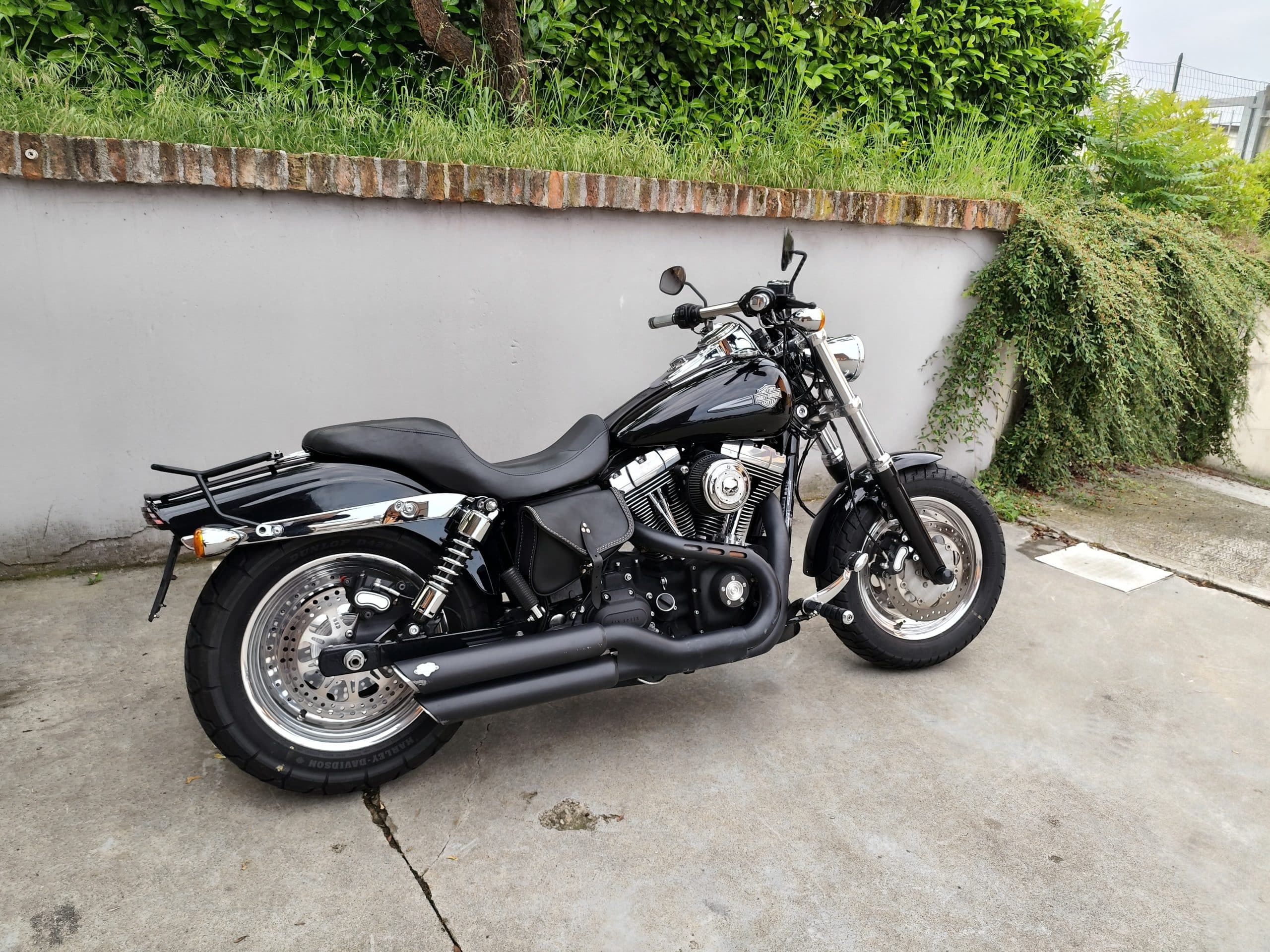 1749819270891.jpg Harley-Davidson nera, modello cruiser, con finiture cromate, motore V-Twin, scarichi neri e sella biposto in pelle. Perfetta per gli amanti dei motori.
