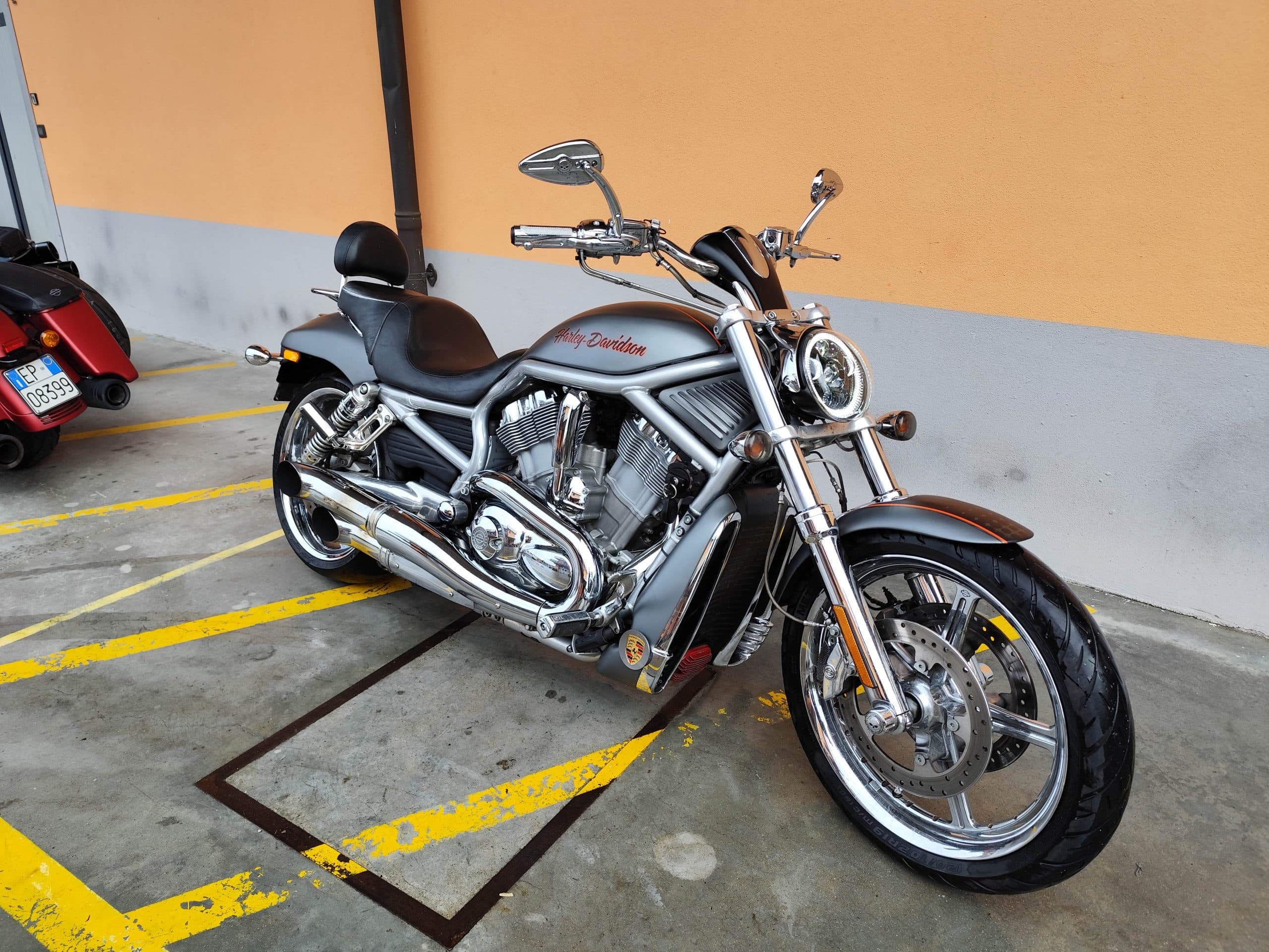 1766134082196.jpg Harley-Davidson V-Rod grigia parcheggiata, con dettagli cromati lucidi, motore V-Twin e design muscoloso, pronta per un test ride.