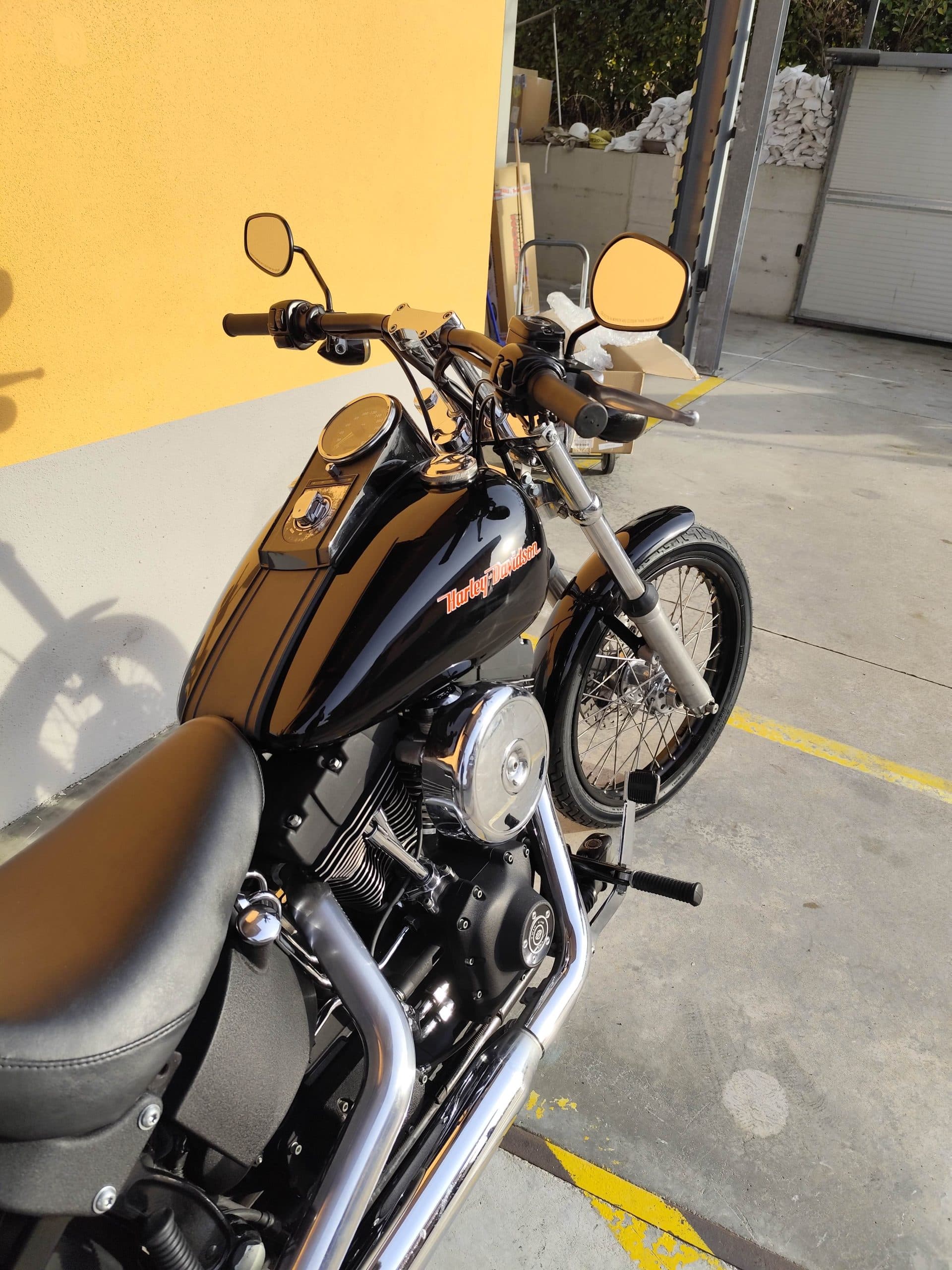 1768227369526.jpg Harley-Davidson nera lucida, con motore V-twin e scarichi cromati, in esposizione all'aperto. Perfetta per gli appassionati di moto