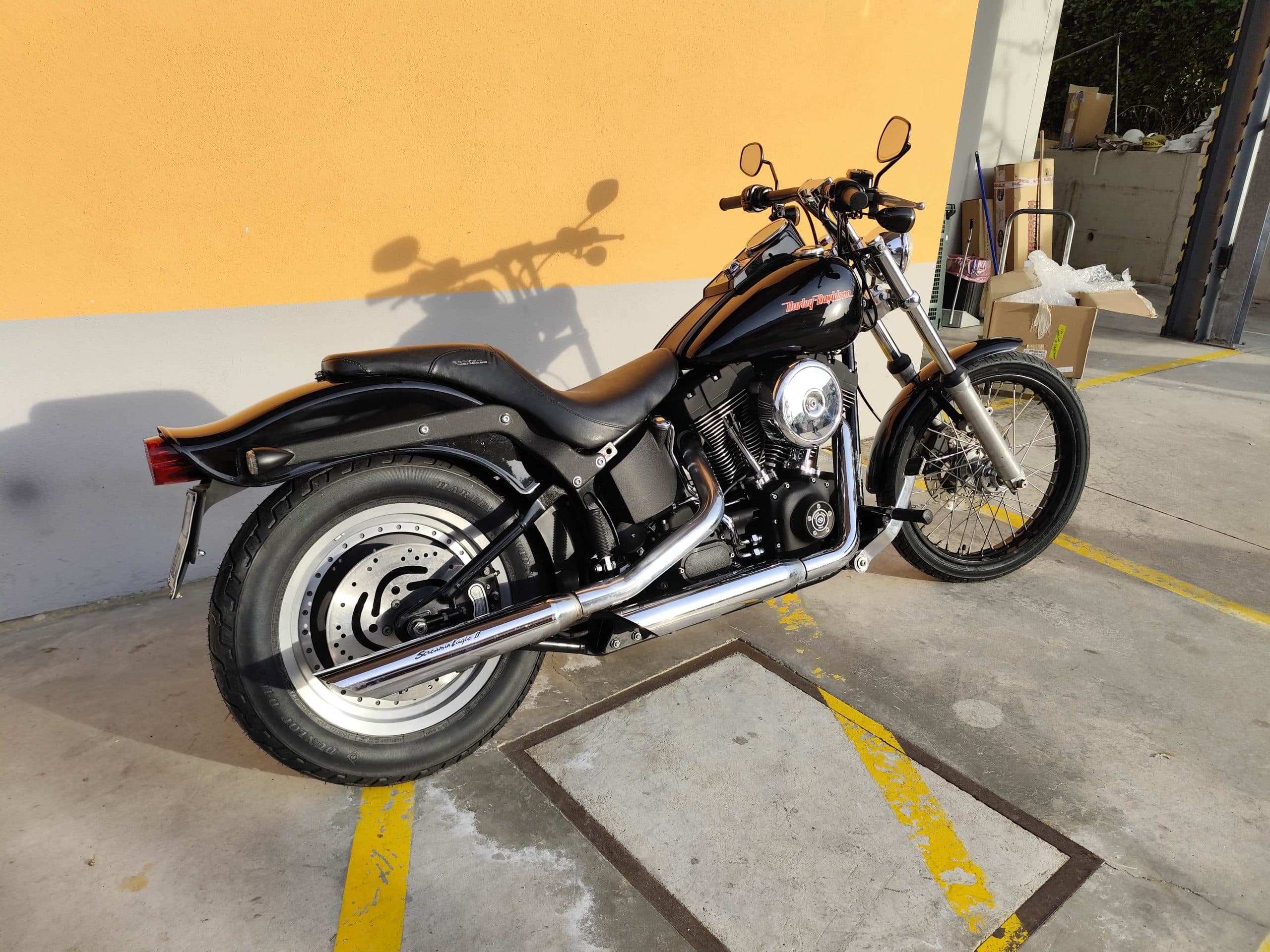 1768227369758.jpg Harley-Davidson nera, modello cruiser, parcheggiata all'aperto con dettagli cromati e scarico Screamin' Eagle II. Ideale per test ride.