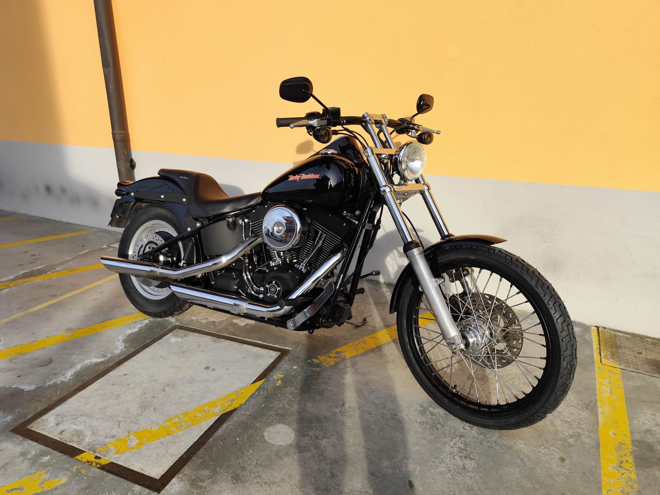 1768227369890.jpg Harley-Davidson nera, modello cruiser, parcheggiata all'aperto con dettagli cromati lucidi e motore V-twin in evidenza, pronta per un test ride.